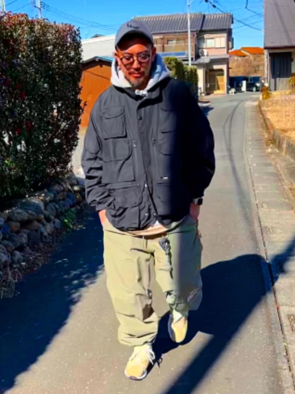 ブラック系のミリタリージャケット、グレー系のパーカー、グリーン系のその他パンツを着用したメンズの冬コーディネートの2枚目の写真