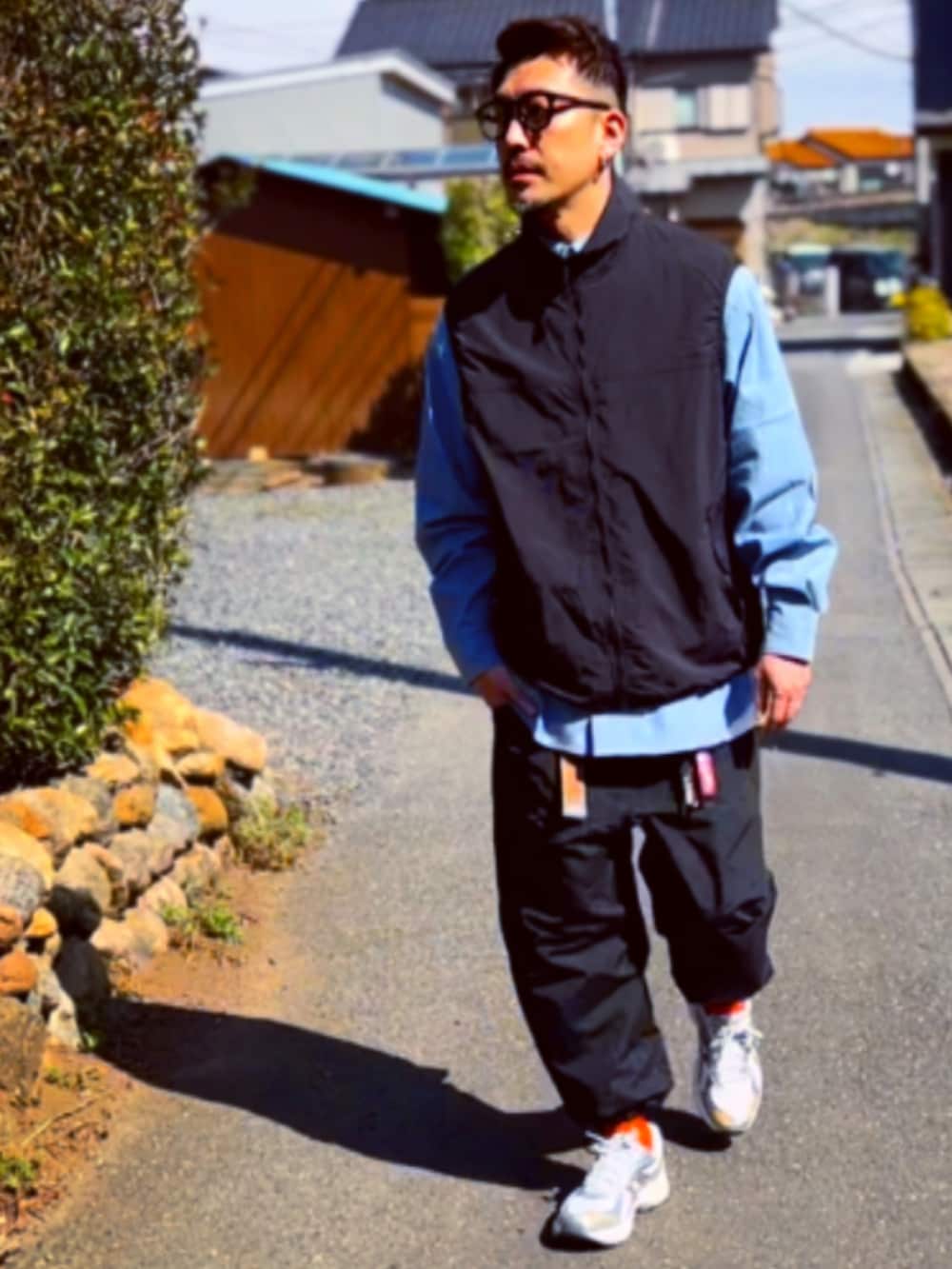 ブラック系のダウンベスト、ブルー系のシャツ/ブラウス、ブラック系のその他パンツを着用したメンズの春コーディネートの2枚目の写真