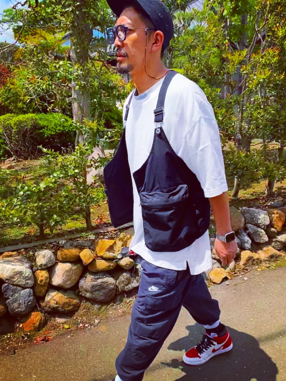 ブラック系のベスト、ホワイト系のTシャツ/カットソー、ブラック系のカーゴパンツを着用したメンズの春コーディネートの4枚目の写真