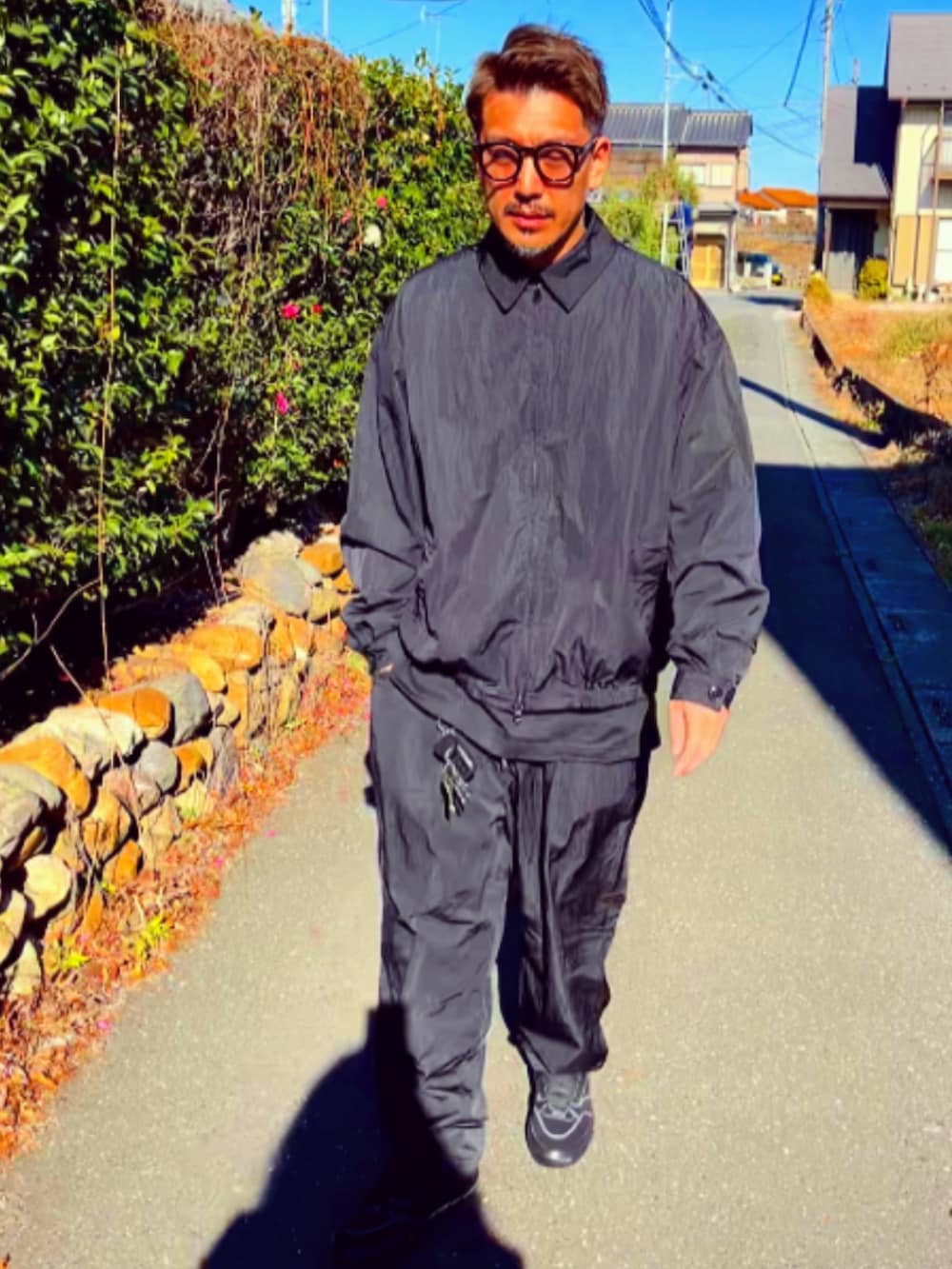 ブラック系のナイロンジャケット、ブラック系のその他パンツ、ブラック系のスニーカーを着用したメンズの冬コーディネートの2枚目の写真