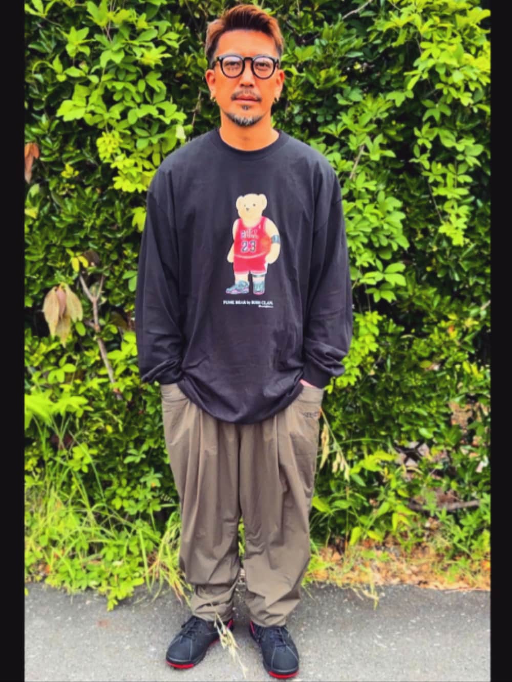 ブラック系のTシャツ/カットソー、グリーン系のその他パンツ、ブラック系のスニーカーを着用したメンズの春コーディネートの2枚目の写真