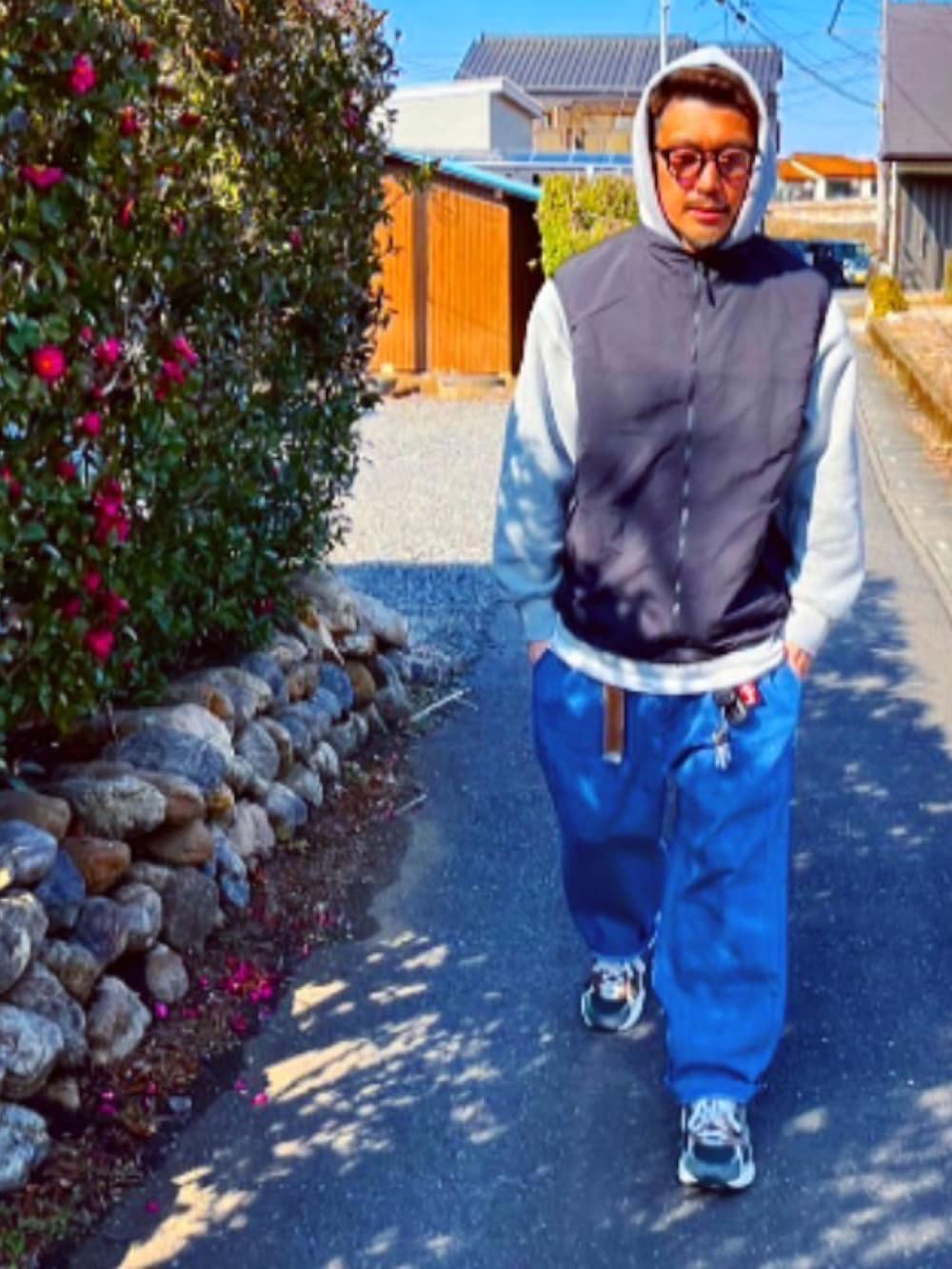 グレー系のパーカー、ブラック系のダウンベスト、ブルー系のデニムパンツを着用したメンズの冬コーディネートの2枚目の写真