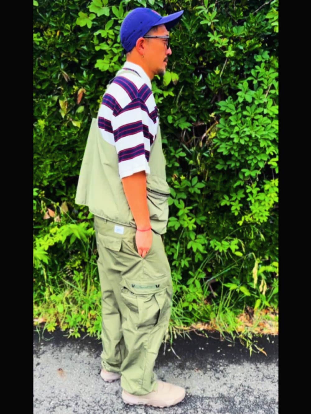 グリーン系のベスト、ホワイト系のポロシャツ、グリーン系のカーゴパンツを着用したメンズの春コーディネートの5枚目の写真