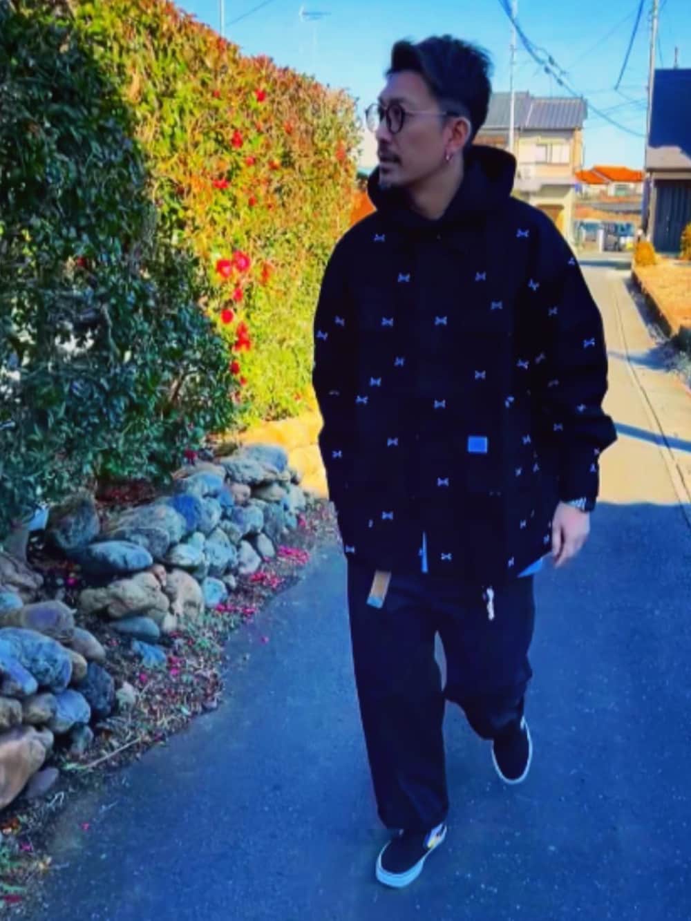 ブラック系のジャケット/アウター、ブラック系のパーカー、レッド系のチノパンツを着用したメンズの冬コーディネートの3枚目の写真