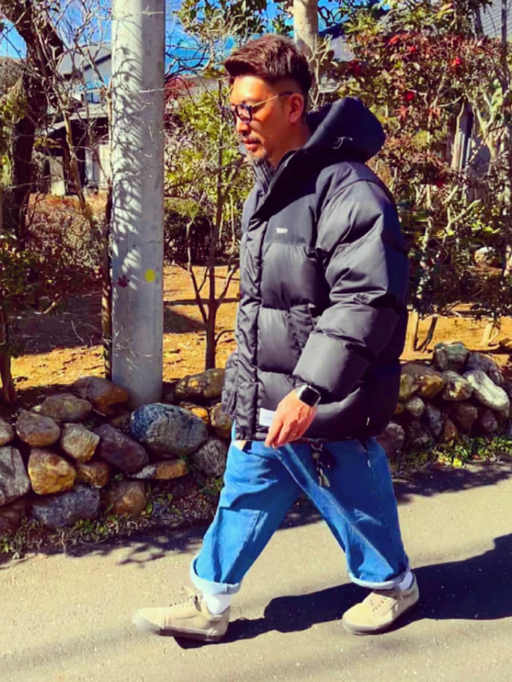 ブラック系のダウンジャケット/コート、ブルー系のデニムパンツ、ブラウン系のスニーカーを着用したメンズの冬コーディネートの5枚目の写真