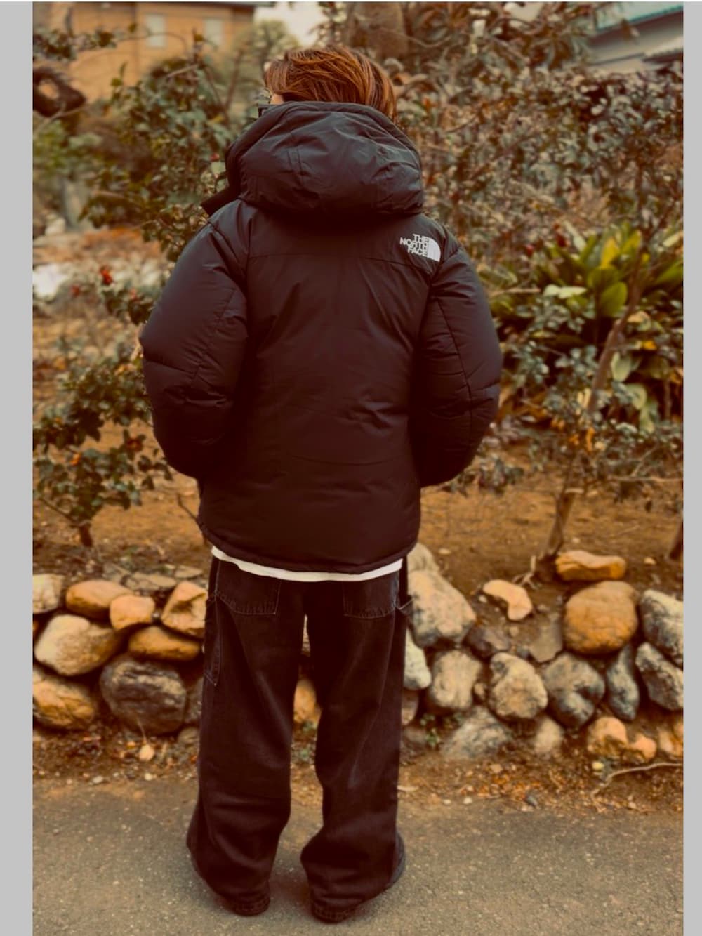 ブラック系のTシャツ/カットソー、ブラック系のダウンジャケット/コート、ブラック系のデニムパンツを着用したメンズの春コーディネートの5枚目の写真