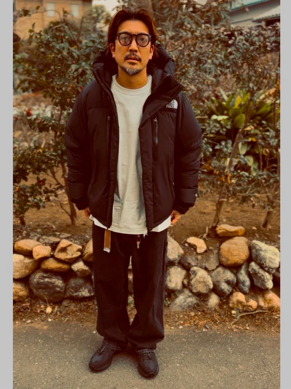 ブラック系のTシャツ/カットソー、ブラック系のダウンジャケット/コート、ブラック系のデニムパンツを着用したメンズの春コーディネートの2枚目の写真