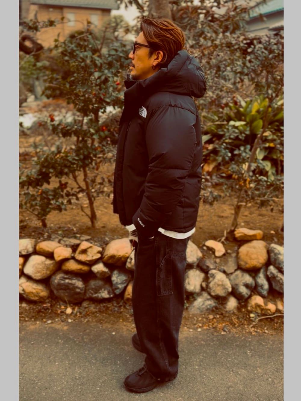 ブラック系のTシャツ/カットソー、ブラック系のダウンジャケット/コート、ブラック系のデニムパンツを着用したメンズの春コーディネートの4枚目の写真