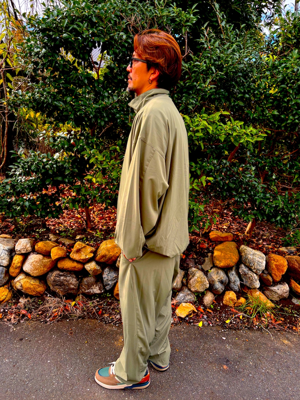 グリーン系のセットアップ、グリーン系のその他パンツ、ブラウン系のスニーカーを着用したメンズの秋コーディネートの4枚目の写真