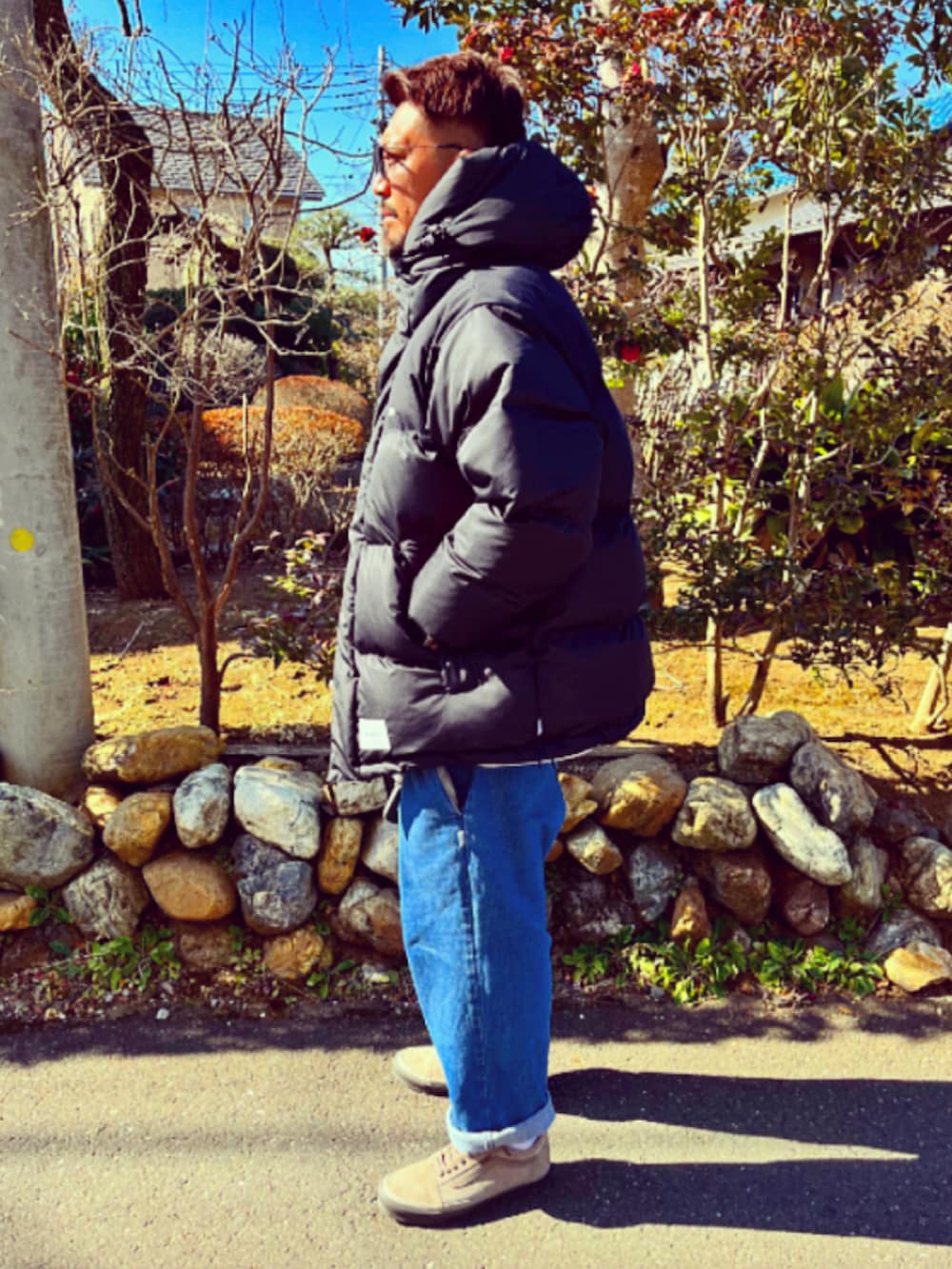 ブラック系のダウンジャケット/コート、ブルー系のデニムパンツ、ブラウン系のスニーカーを着用したメンズの冬コーディネートの2枚目の写真