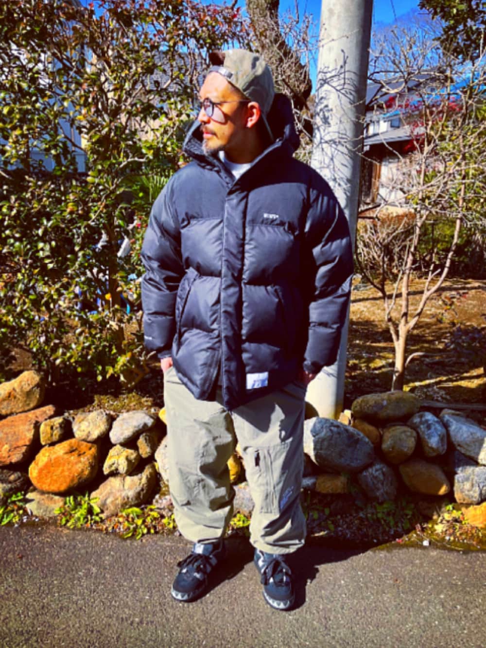 ブラック系のダウンジャケット/コート、グリーン系のその他パンツ、ブラック系のスニーカーを着用したメンズの冬コーディネートの2枚目の写真