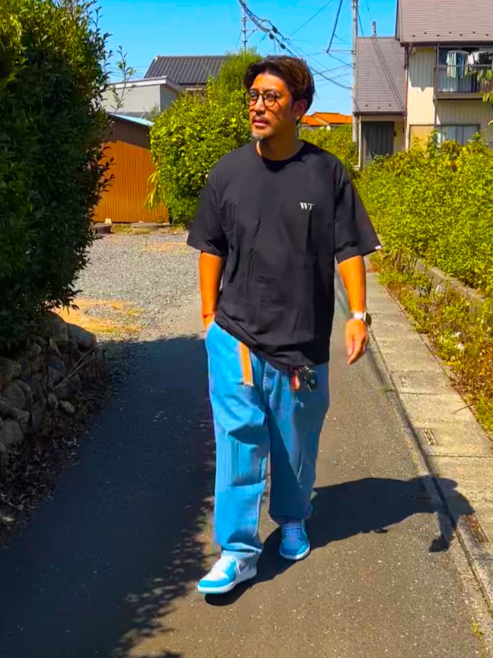 ブラック系のTシャツ/カットソー、ブルー系のデニムパンツ、ブルー系のスニーカーを着用したメンズの秋コーディネートの2枚目の写真