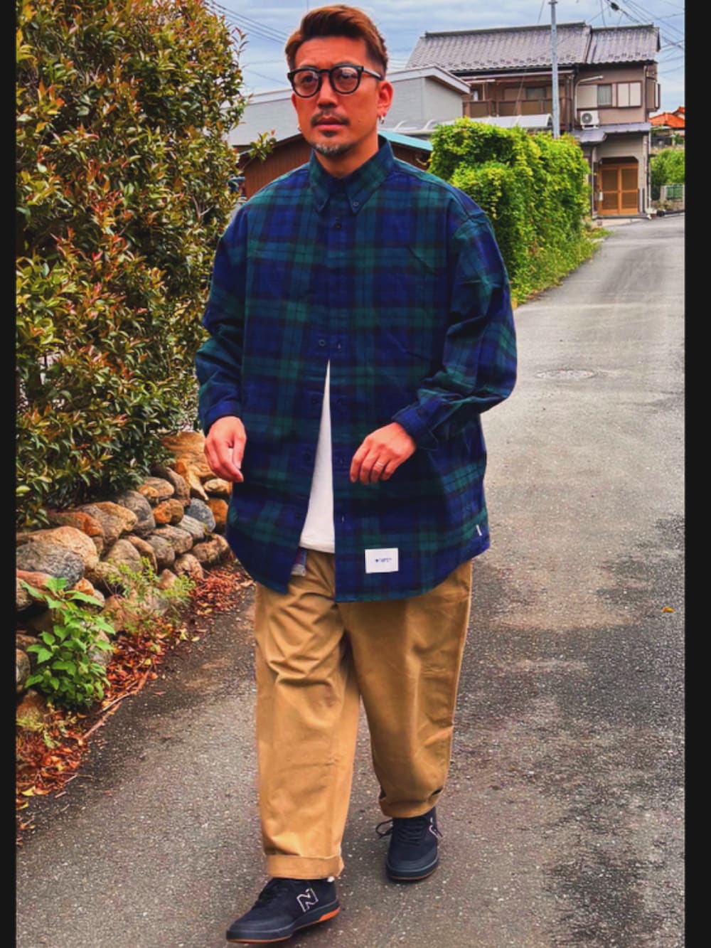 グリーン系のシャツ/ブラウス、ベージュ系のチノパンツ、ブラック系のスニーカーを着用したメンズの春コーディネートの4枚目の写真