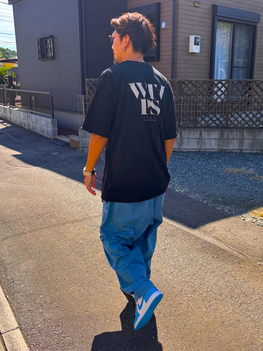 ブラック系のTシャツ/カットソー、ブルー系のデニムパンツ、ブルー系のスニーカーを着用したメンズの秋コーディネートの5枚目の写真