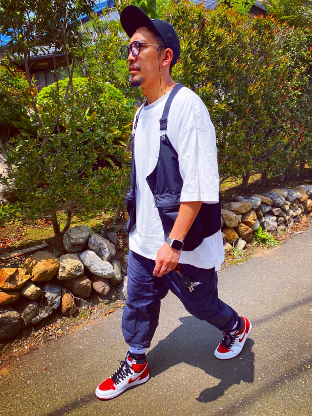 ブラック系のベスト、ホワイト系のTシャツ/カットソー、ブラック系のカーゴパンツを着用したメンズの春コーディネートの3枚目の写真