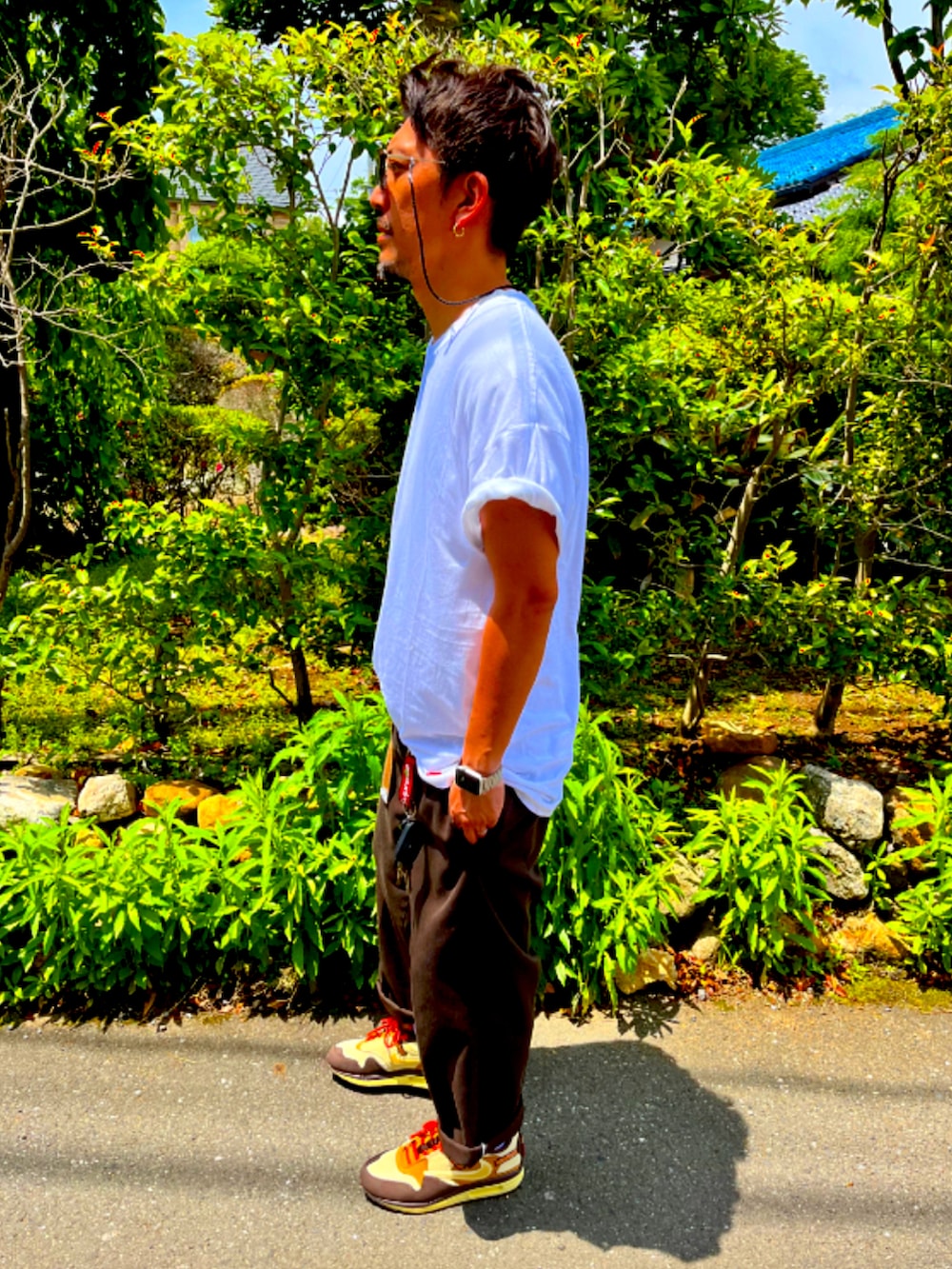 ホワイト系のTシャツ/カットソー、レッド系のチノパンツ、ブラウン系のスニーカーを着用したメンズの夏コーディネートの4枚目の写真