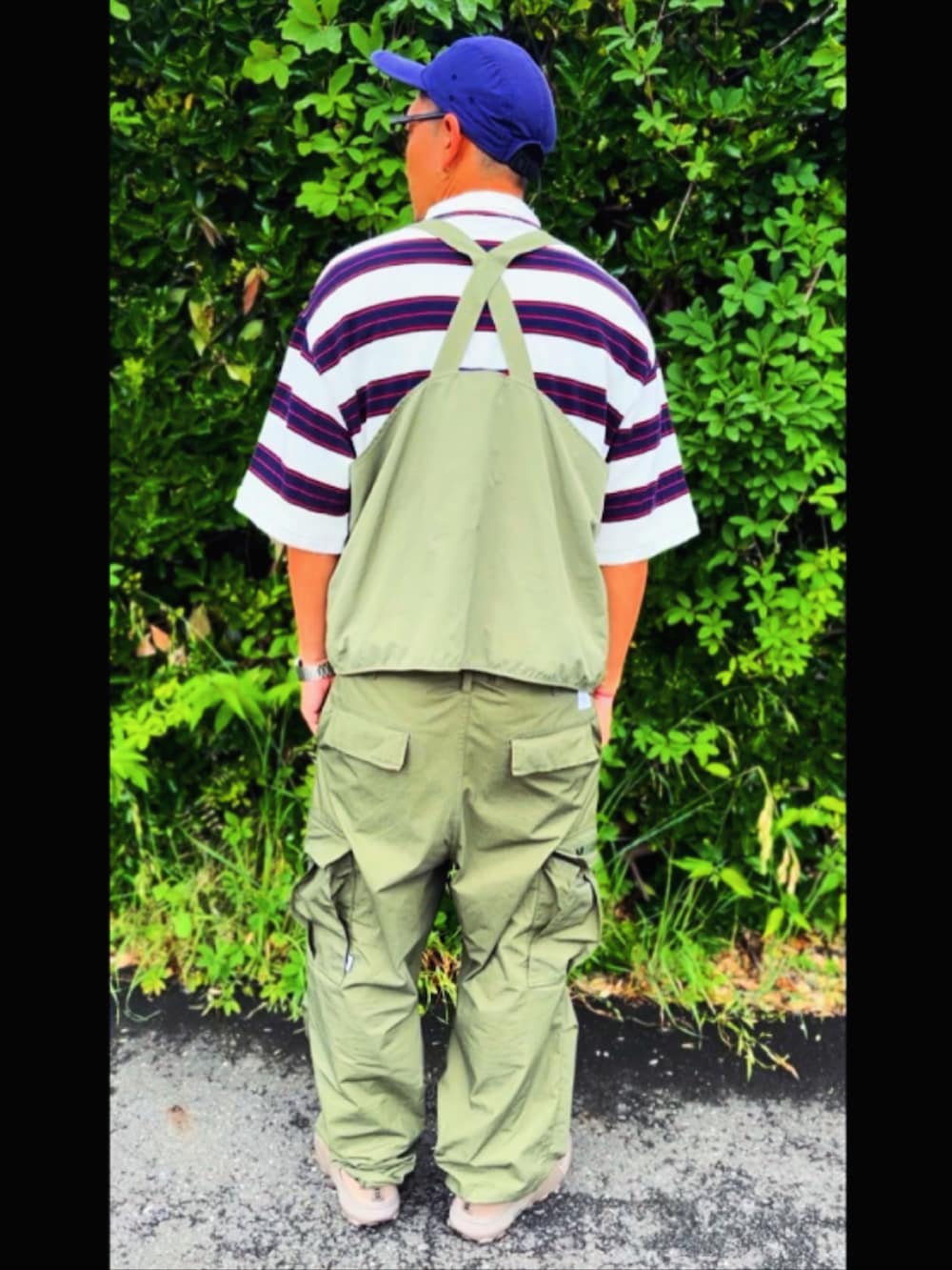 グリーン系のベスト、ホワイト系のポロシャツ、グリーン系のカーゴパンツを着用したメンズの春コーディネートの4枚目の写真