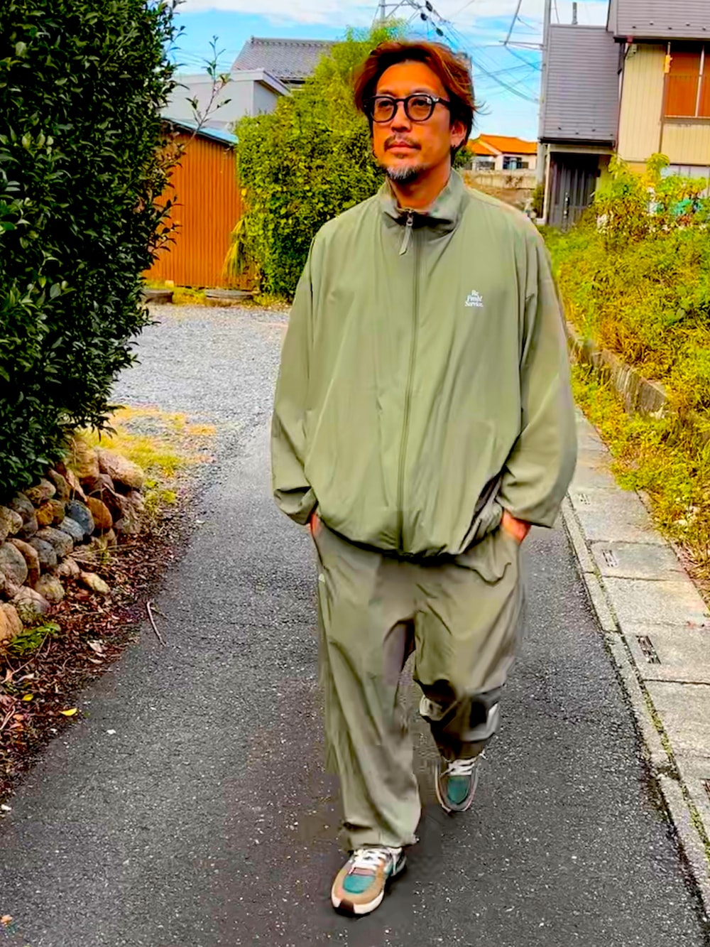 グリーン系のセットアップ、グリーン系のその他パンツ、ブラウン系のスニーカーを着用したメンズの秋コーディネートの2枚目の写真