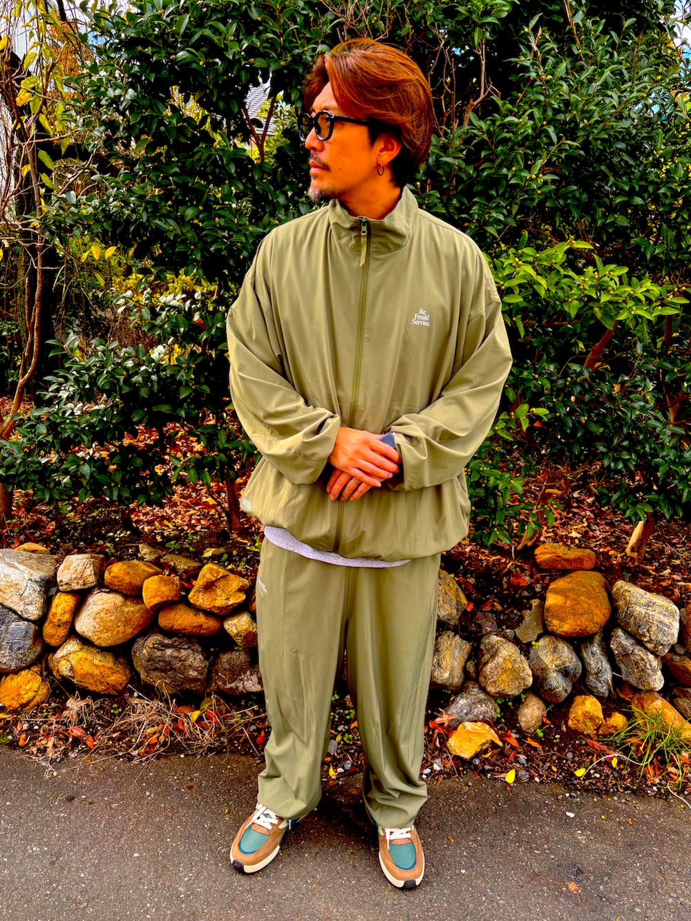 グリーン系のセットアップ、グリーン系のその他パンツ、ブラウン系のスニーカーを着用したメンズの秋コーディネートの3枚目の写真