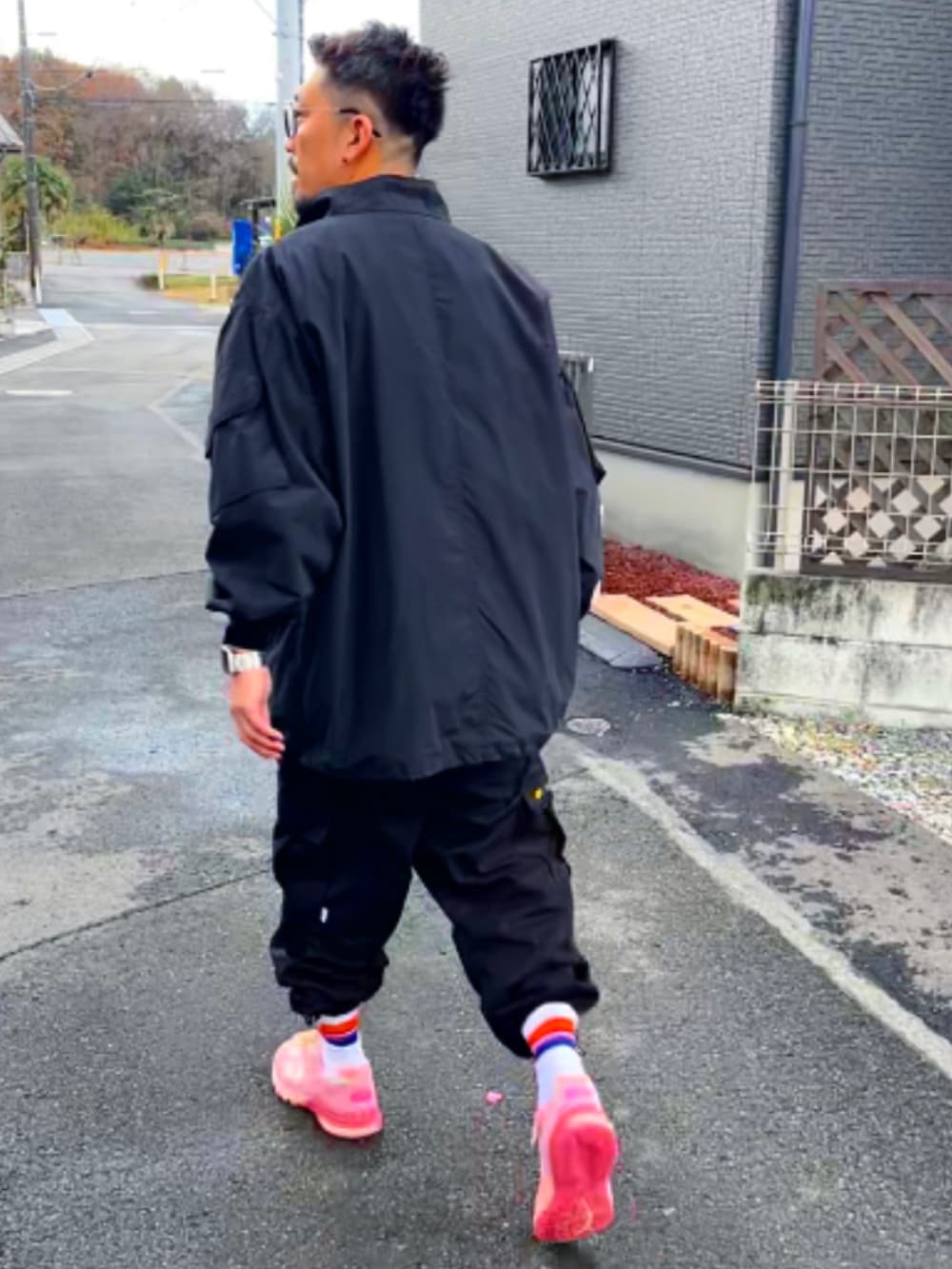 ブラック系のミリタリージャケット、ピンク系のTシャツ/カットソー、ブラック系のカーゴパンツを着用したメンズの冬コーディネートの5枚目の写真