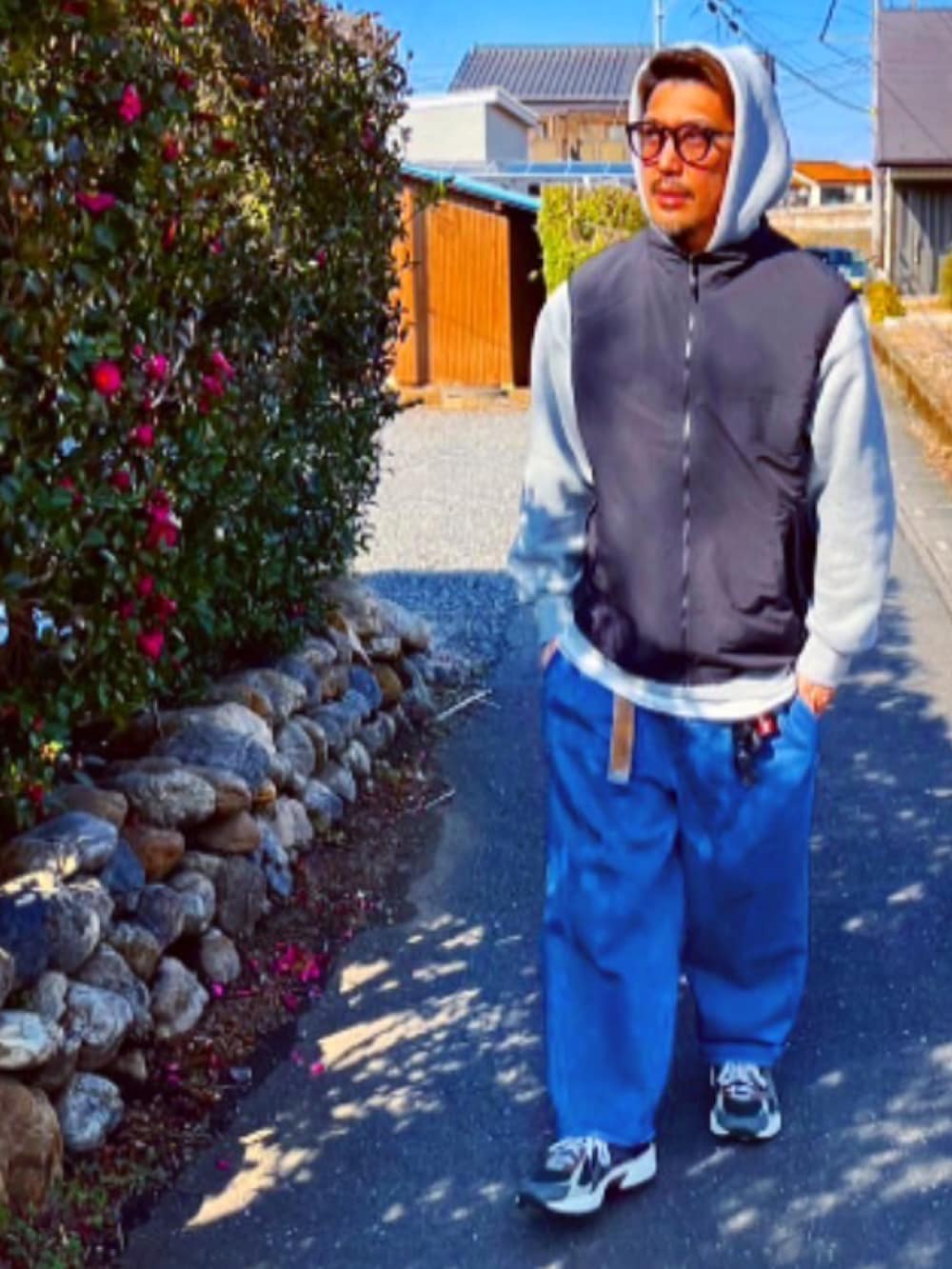 グレー系のパーカー、ブラック系のダウンベスト、ブルー系のデニムパンツを着用したメンズの冬コーディネートの3枚目の写真