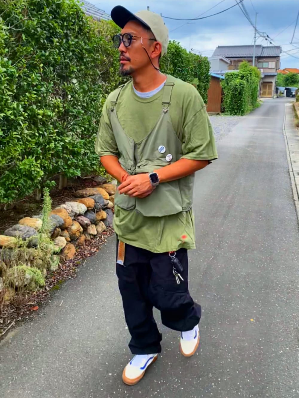 グリーン系のベスト、グリーン系のTシャツ/カットソー、ブラック系のカーゴパンツを着用したメンズの秋コーディネートの5枚目の写真