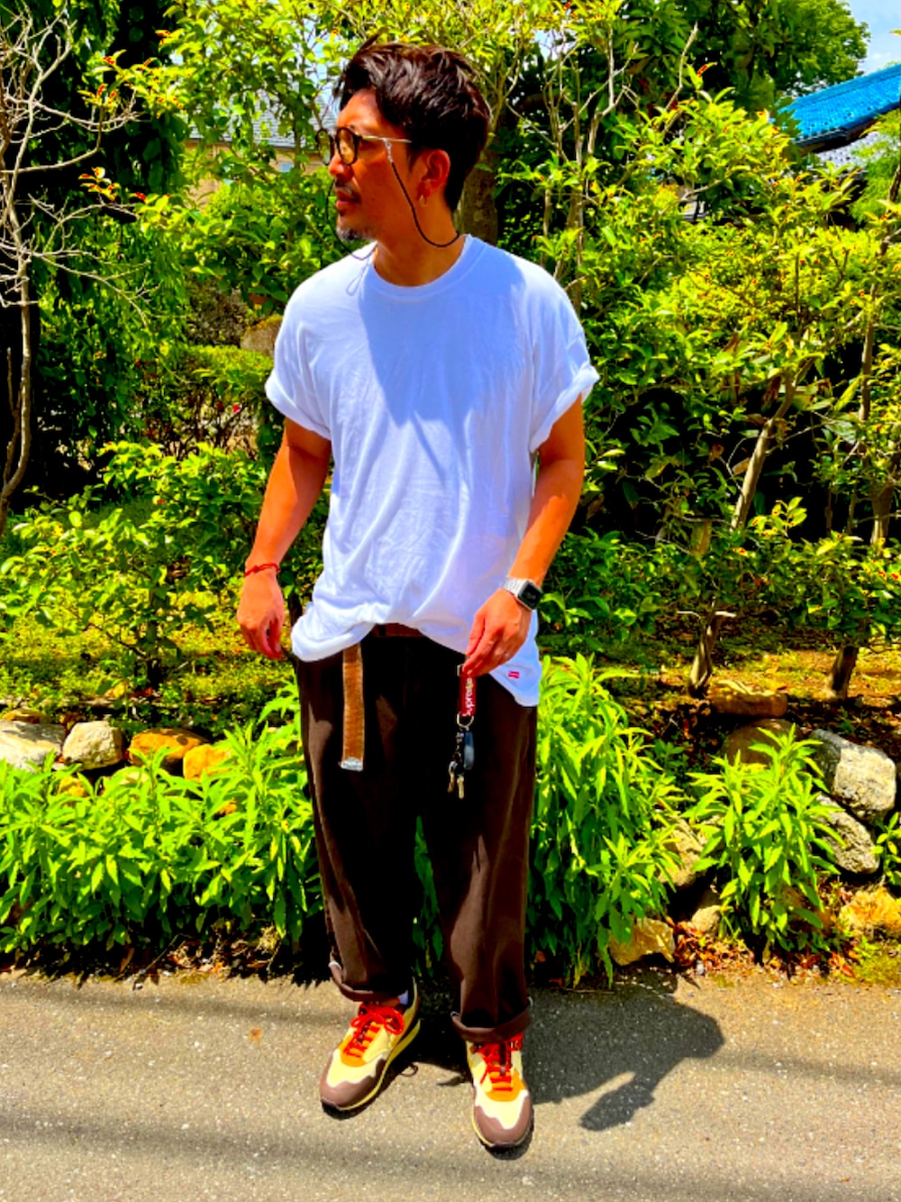 ホワイト系のTシャツ/カットソー、レッド系のチノパンツ、ブラウン系のスニーカーを着用したメンズの夏コーディネートの3枚目の写真