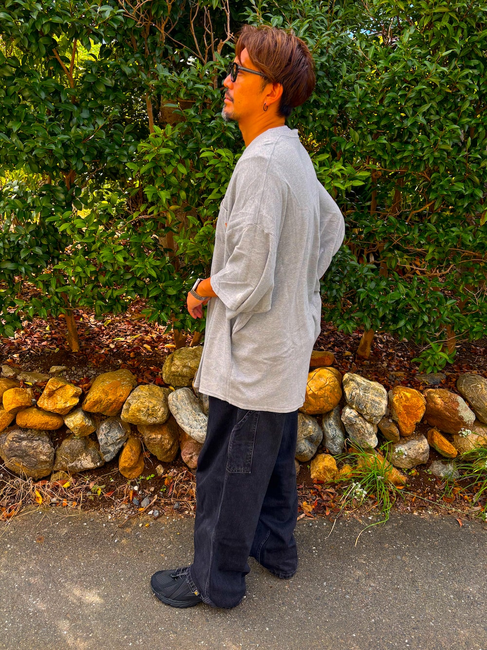 グレー系のTシャツ/カットソー、ブラック系のデニムパンツ、ブラック系のスニーカーを着用したメンズの秋コーディネートの5枚目の写真