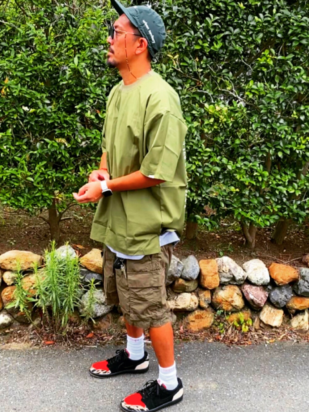 グリーン系のTシャツ/カットソー、ブラック系のパンツ、ブラック系のスニーカーを着用したメンズの夏コーディネートの2枚目の写真