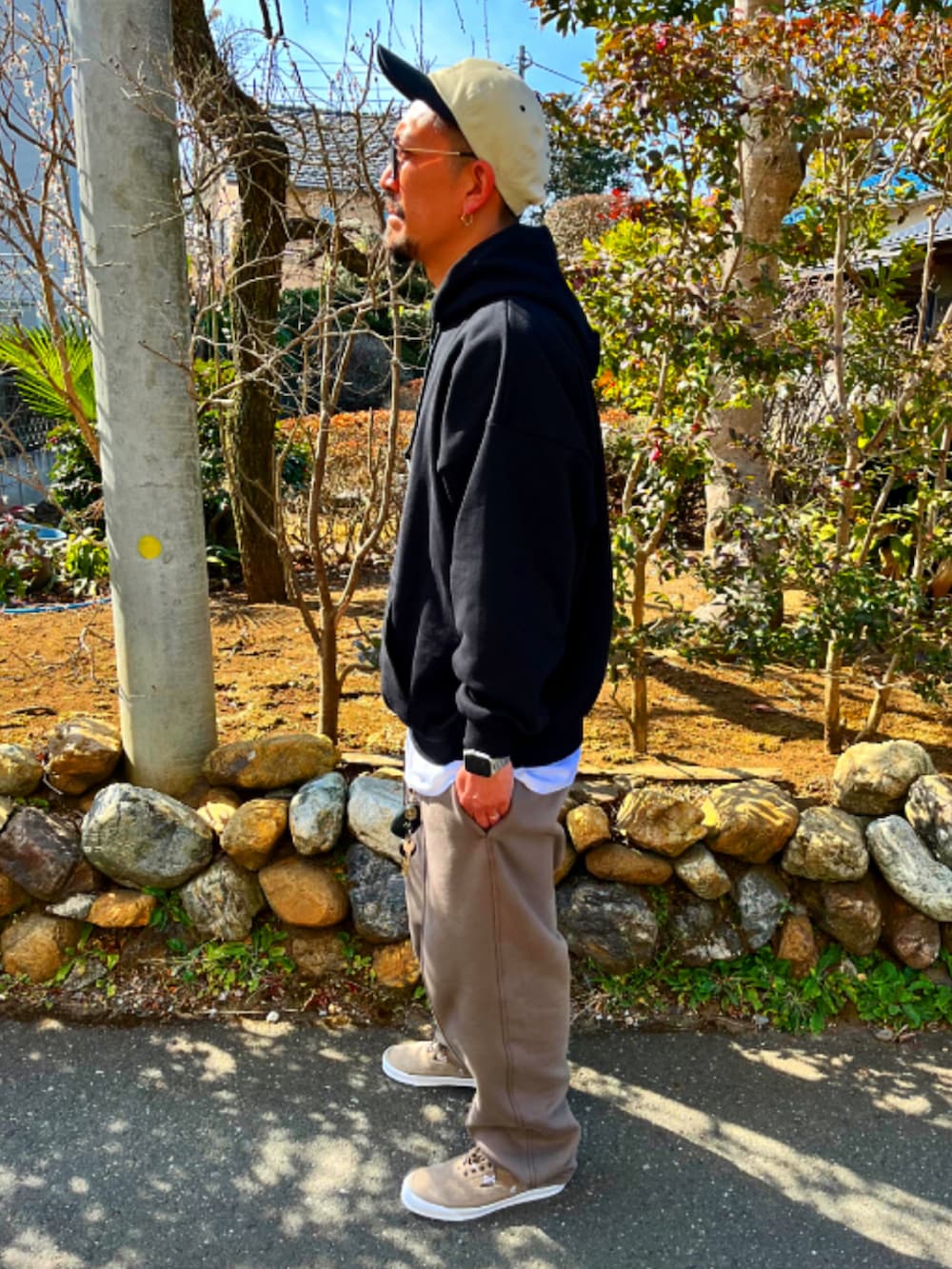 ブラック系のパーカー、ホワイト系のTシャツ/カットソー、ベージュ系のスウェットパンツを着用したメンズの春コーディネートの2枚目の写真
