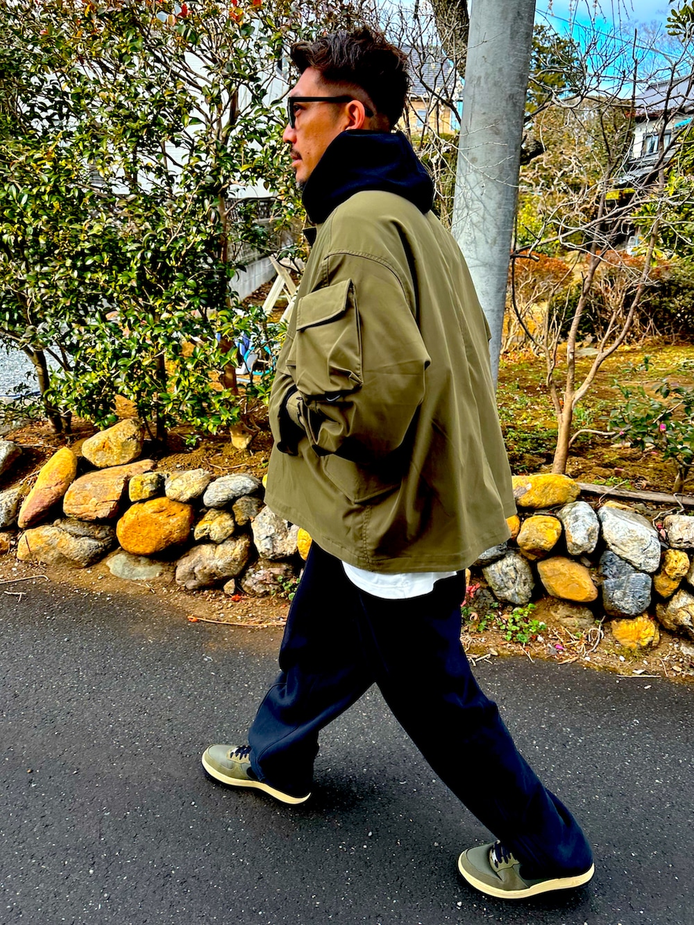 ブラック系のパーカー、グリーン系のミリタリージャケット、ベージュ系のスウェットパンツを着用したメンズの冬コーディネートの4枚目の写真