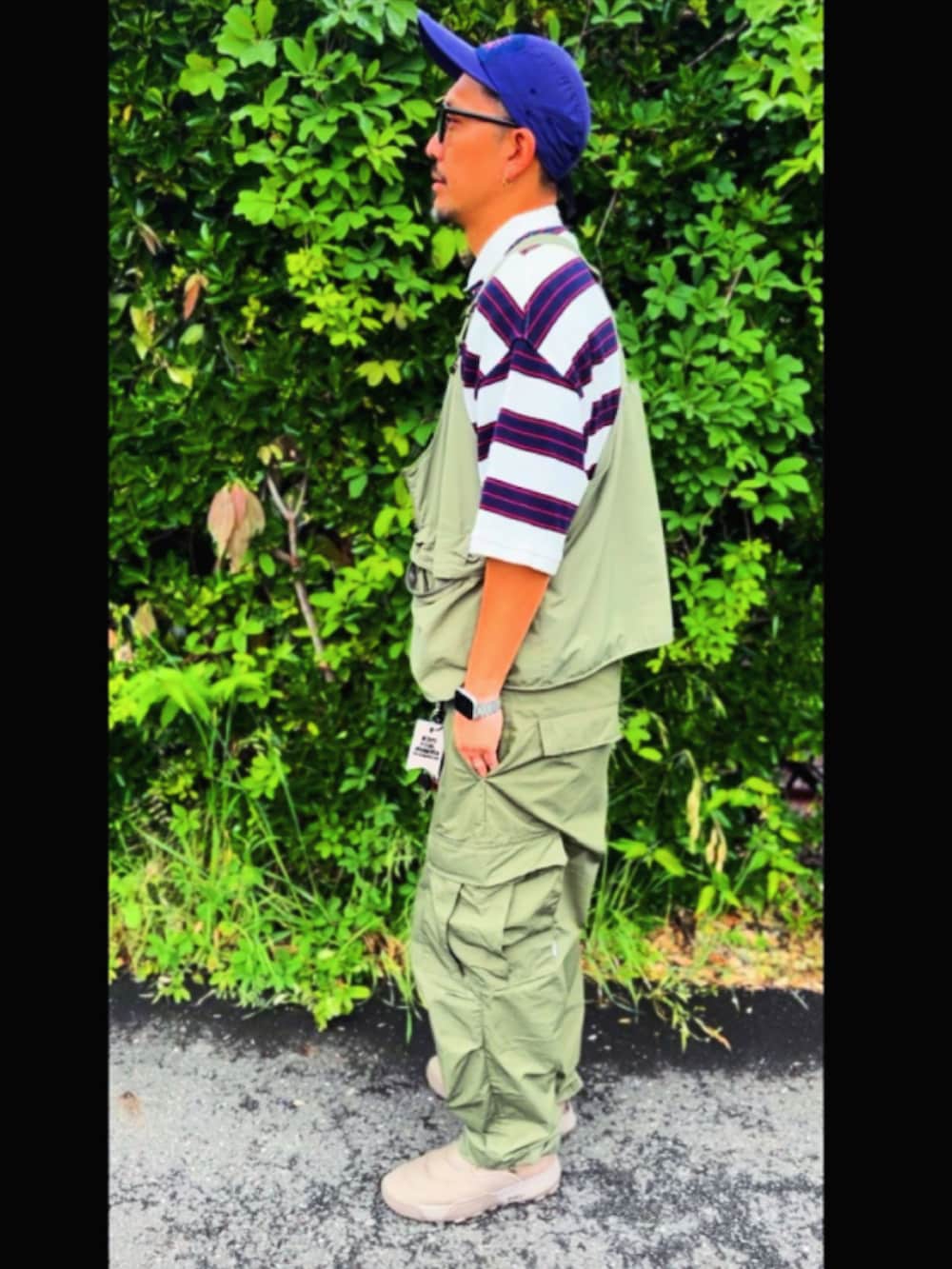 グリーン系のベスト、ホワイト系のポロシャツ、グリーン系のカーゴパンツを着用したメンズの春コーディネートの3枚目の写真