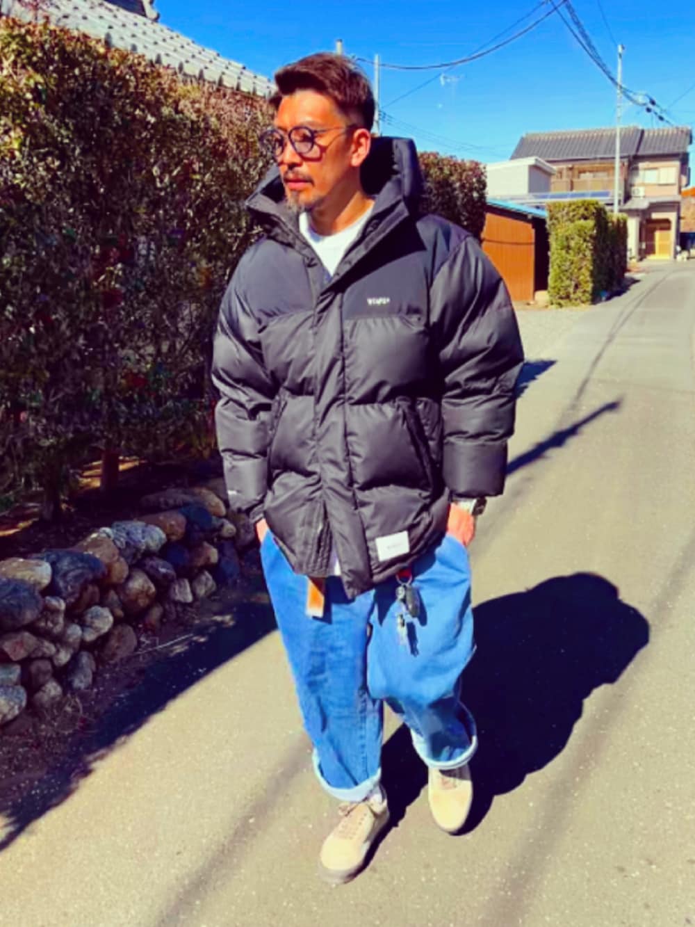 ブラック系のダウンジャケット/コート、ブルー系のデニムパンツ、ブラウン系のスニーカーを着用したメンズの冬コーディネートの3枚目の写真