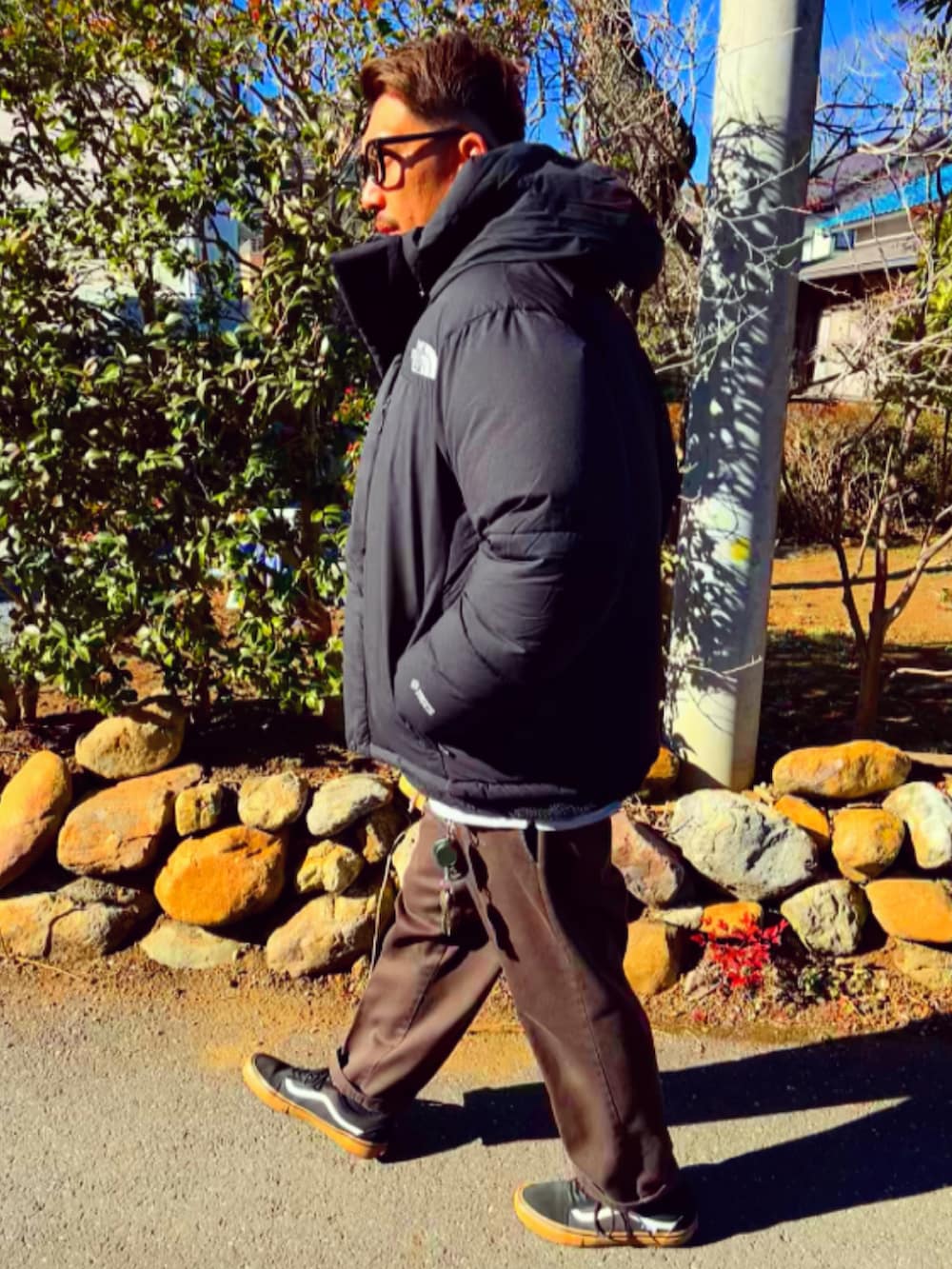 ブラック系のダウンジャケット/コート、ブラック系のナイロンジャケット、レッド系のチノパンツを着用したメンズの冬コーディネートの5枚目の写真