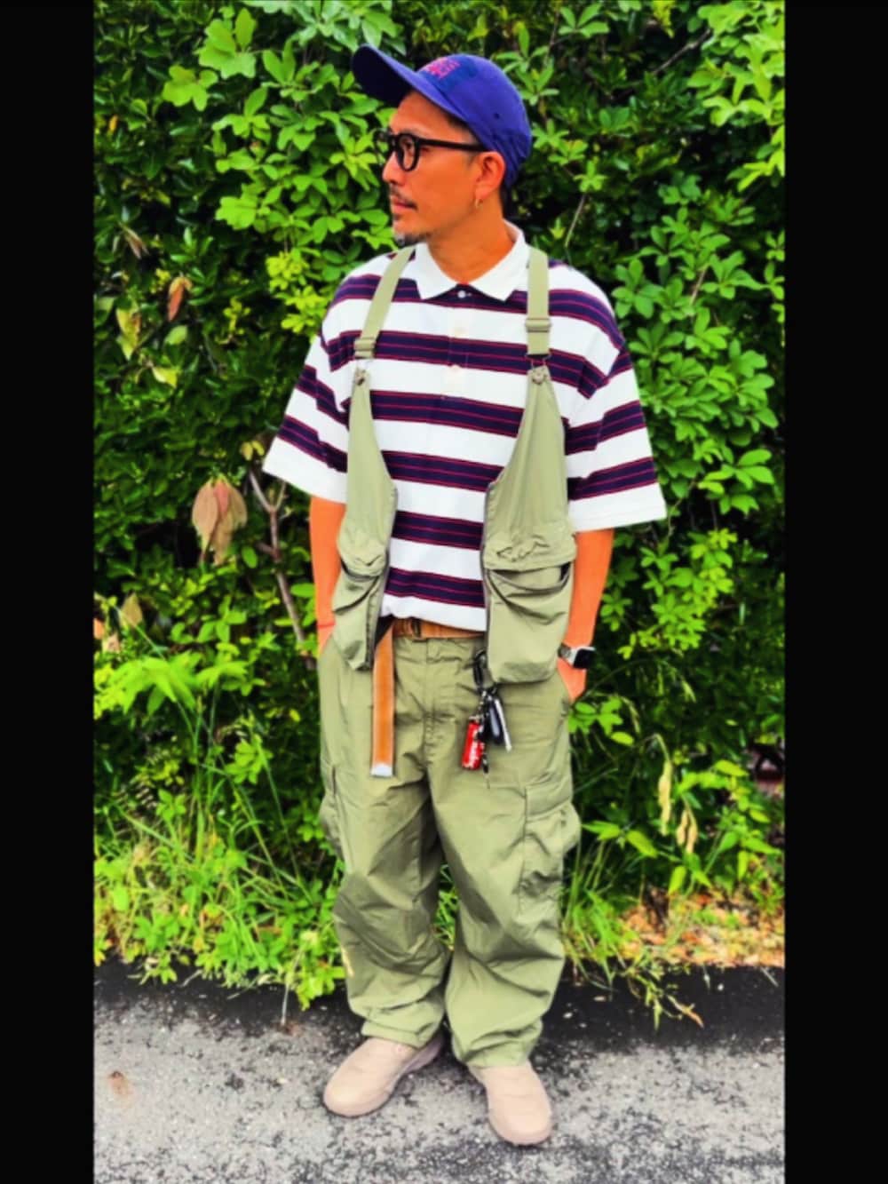 グリーン系のベスト、ホワイト系のポロシャツ、グリーン系のカーゴパンツを着用したメンズの春コーディネートの2枚目の写真