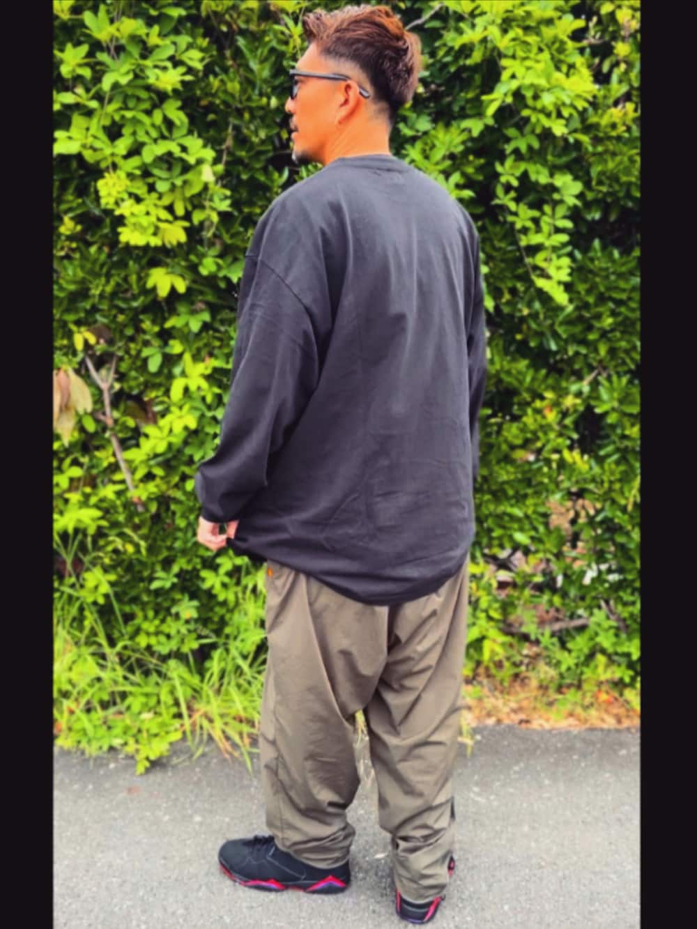 ブラック系のTシャツ/カットソー、グリーン系のその他パンツ、ブラック系のスニーカーを着用したメンズの春コーディネートの4枚目の写真