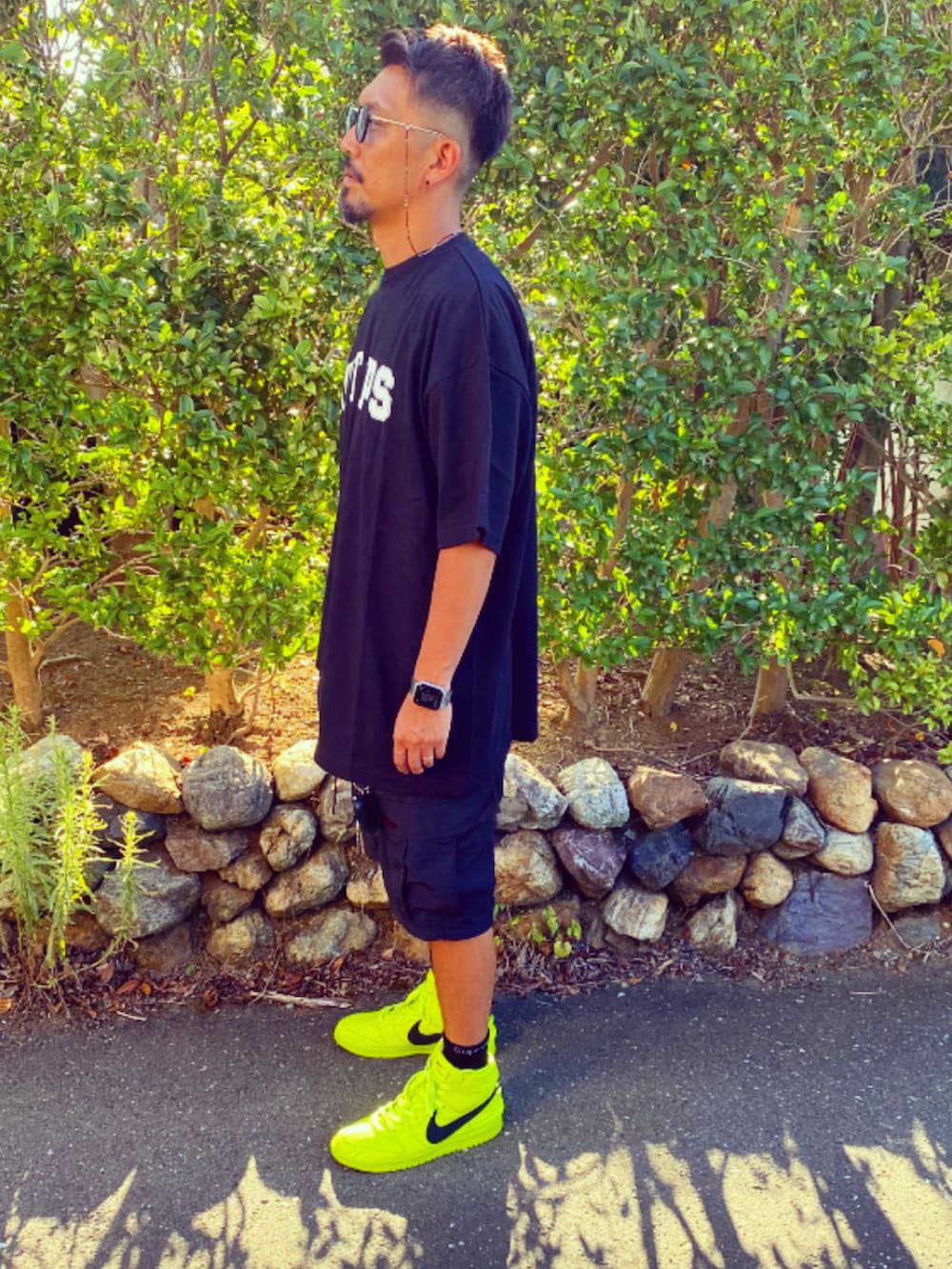 ブラック系のTシャツ/カットソー、ブラック系のカーゴパンツ、イエロー系のスニーカーを着用したメンズの夏コーディネートの2枚目の写真