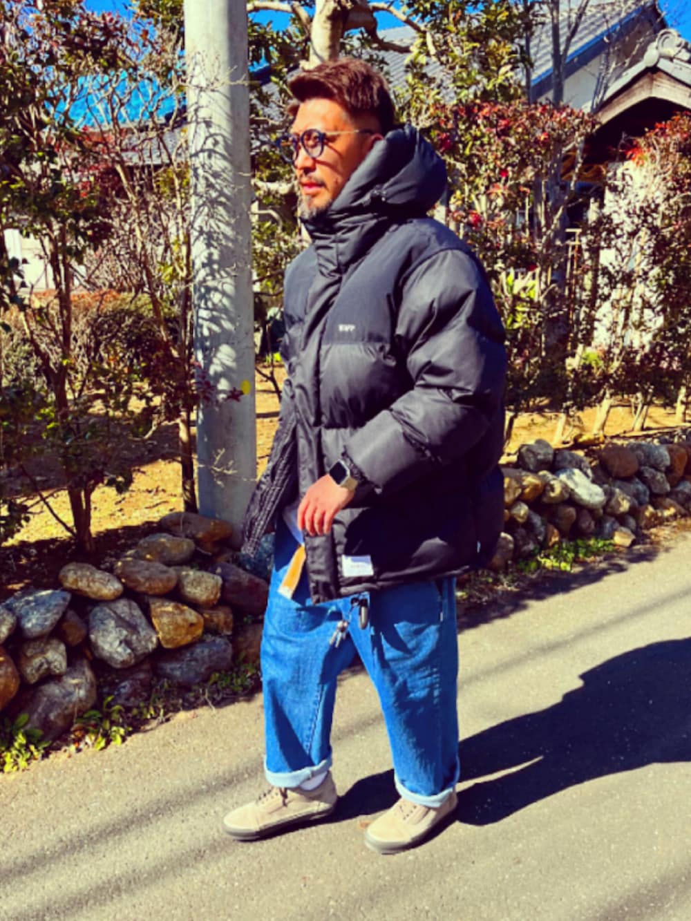 ブラック系のダウンジャケット/コート、ブルー系のデニムパンツ、ブラウン系のスニーカーを着用したメンズの冬コーディネートの4枚目の写真