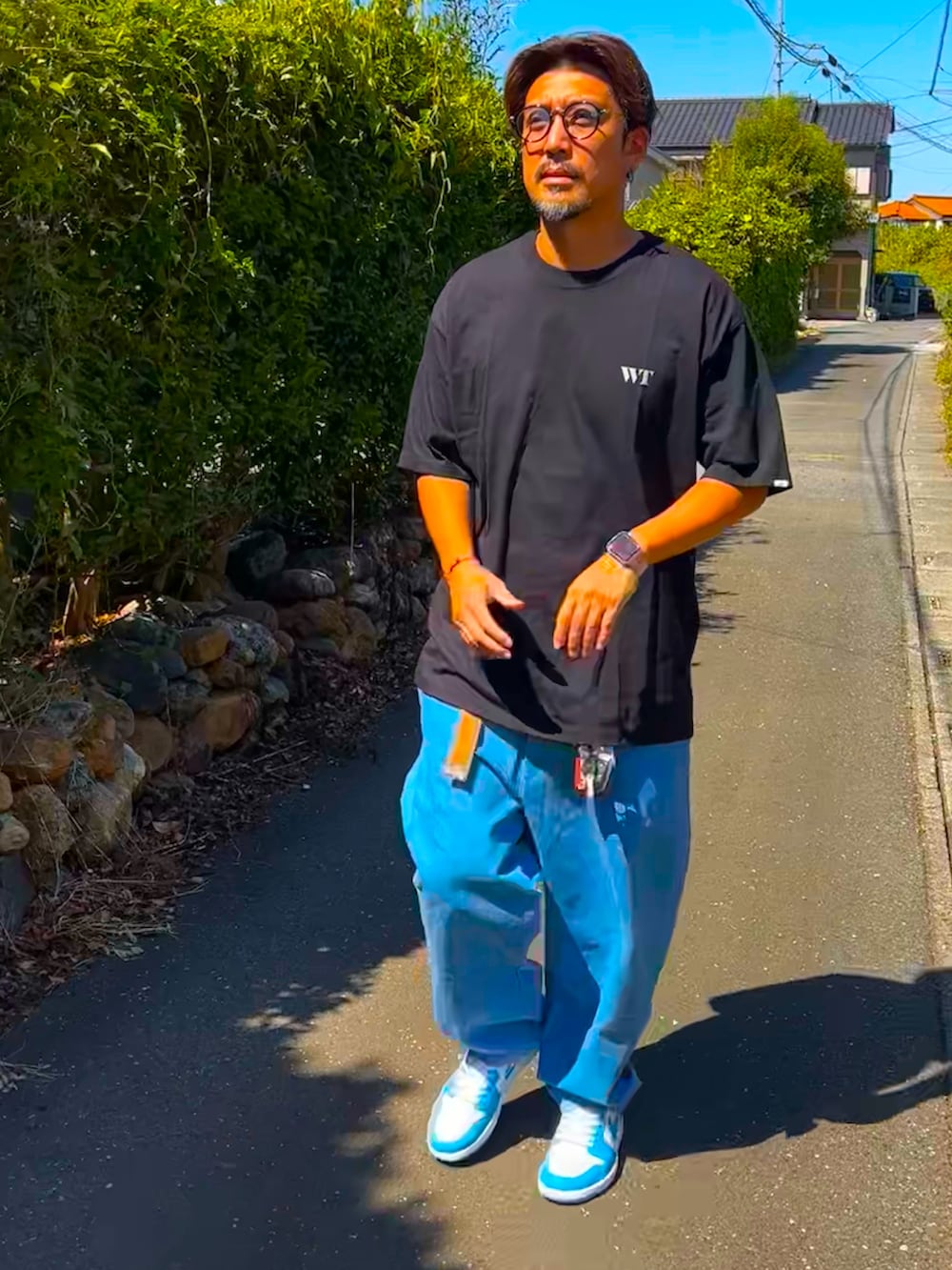 ブラック系のTシャツ/カットソー、ブルー系のデニムパンツ、ブルー系のスニーカーを着用したメンズの秋コーディネートの3枚目の写真