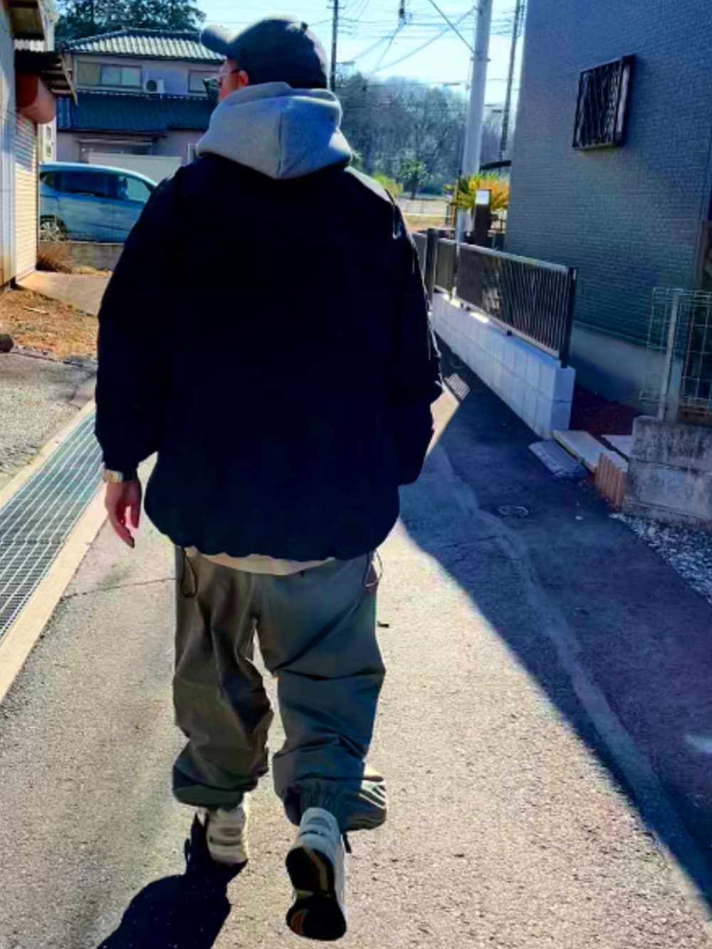 ブラック系のミリタリージャケット、グレー系のパーカー、グリーン系のその他パンツを着用したメンズの冬コーディネートの5枚目の写真