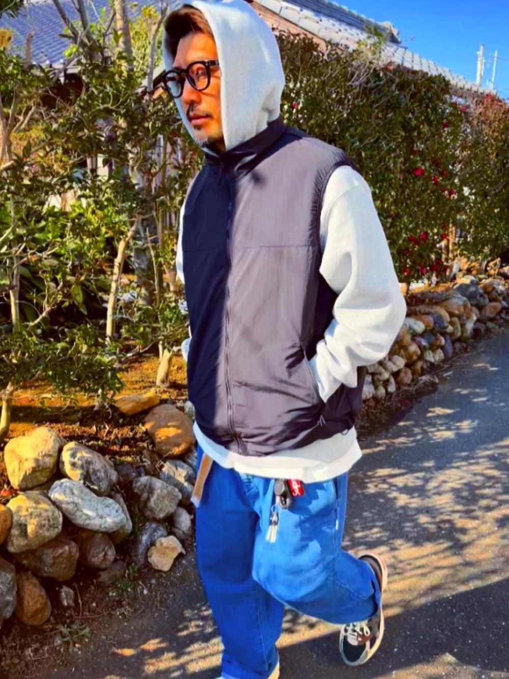 グレー系のパーカー、ブラック系のダウンベスト、ブルー系のデニムパンツを着用したメンズの冬コーディネートの5枚目の写真