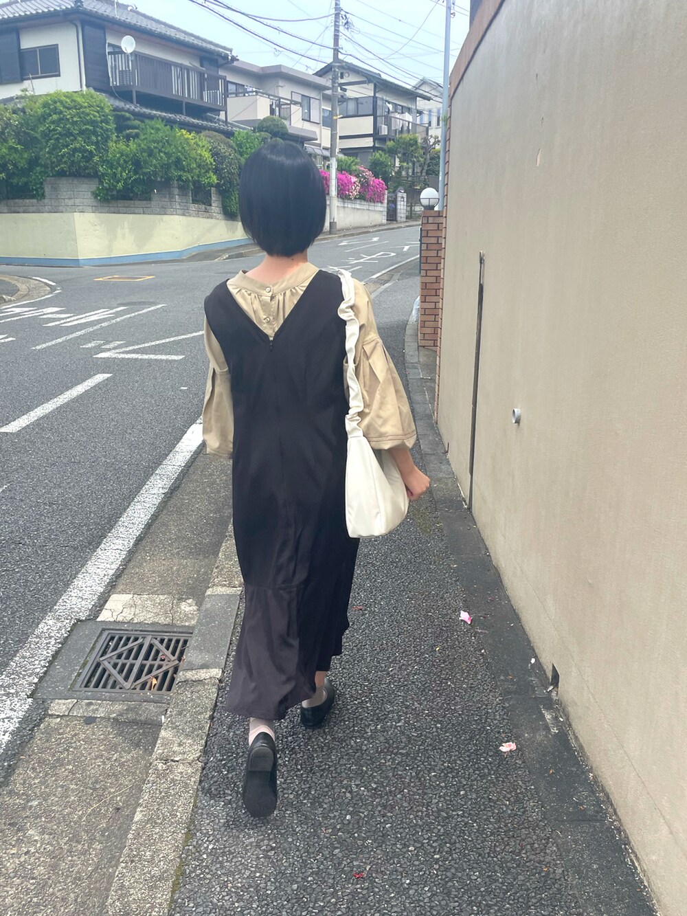 ブラック系のジャンパースカート、ホワイト系のショルダーバッグ、ブラック系のパンプスを着用したレディースの春コーディネートの2枚目の写真