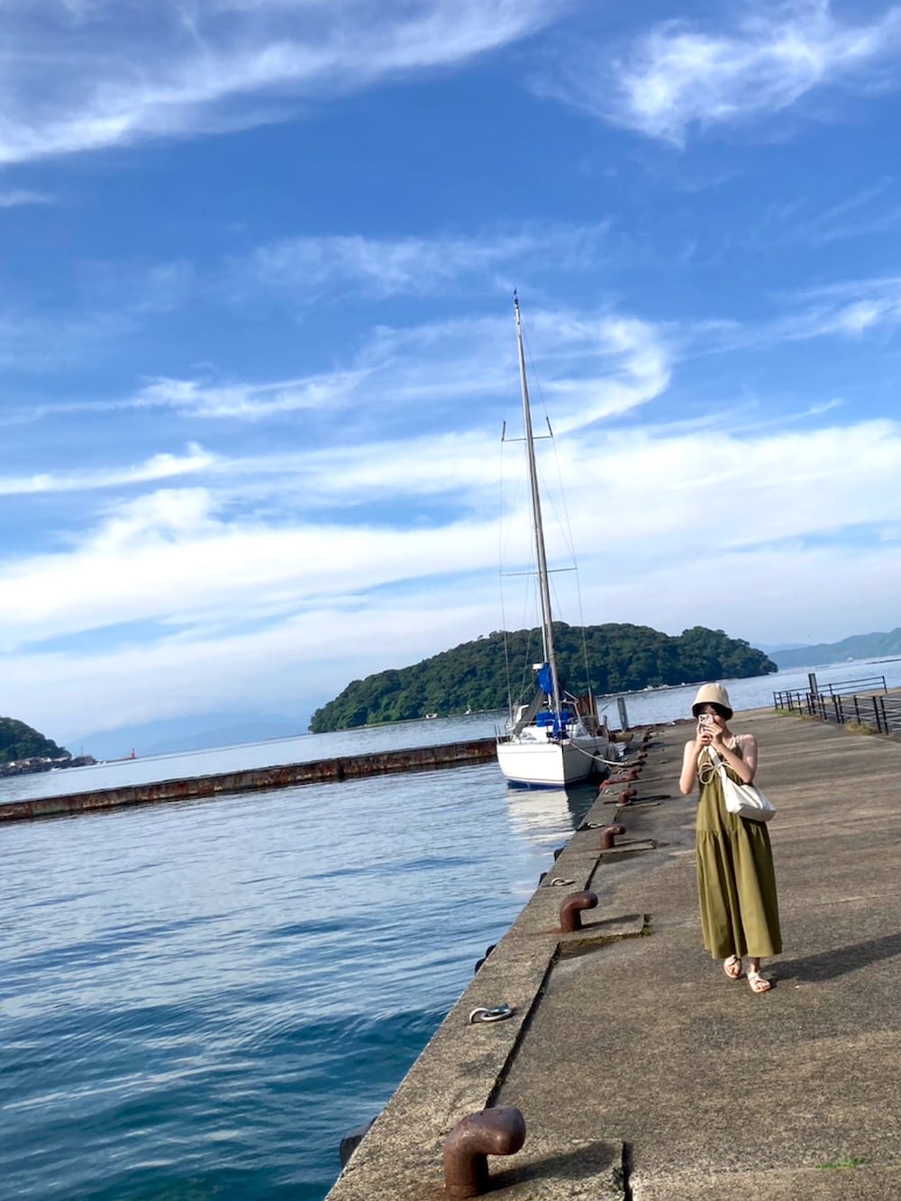 グリーン系のワンピース、ホワイト系のショルダーバッグを着用したレディースの夏コーディネートの3枚目の写真