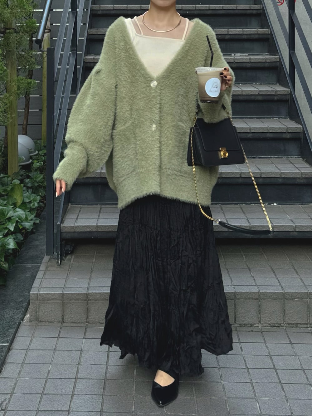 グリーン系のカーディガン/ボレロ、ブラック系のスカートを着用したレディースの秋コーディネートの3枚目の写真