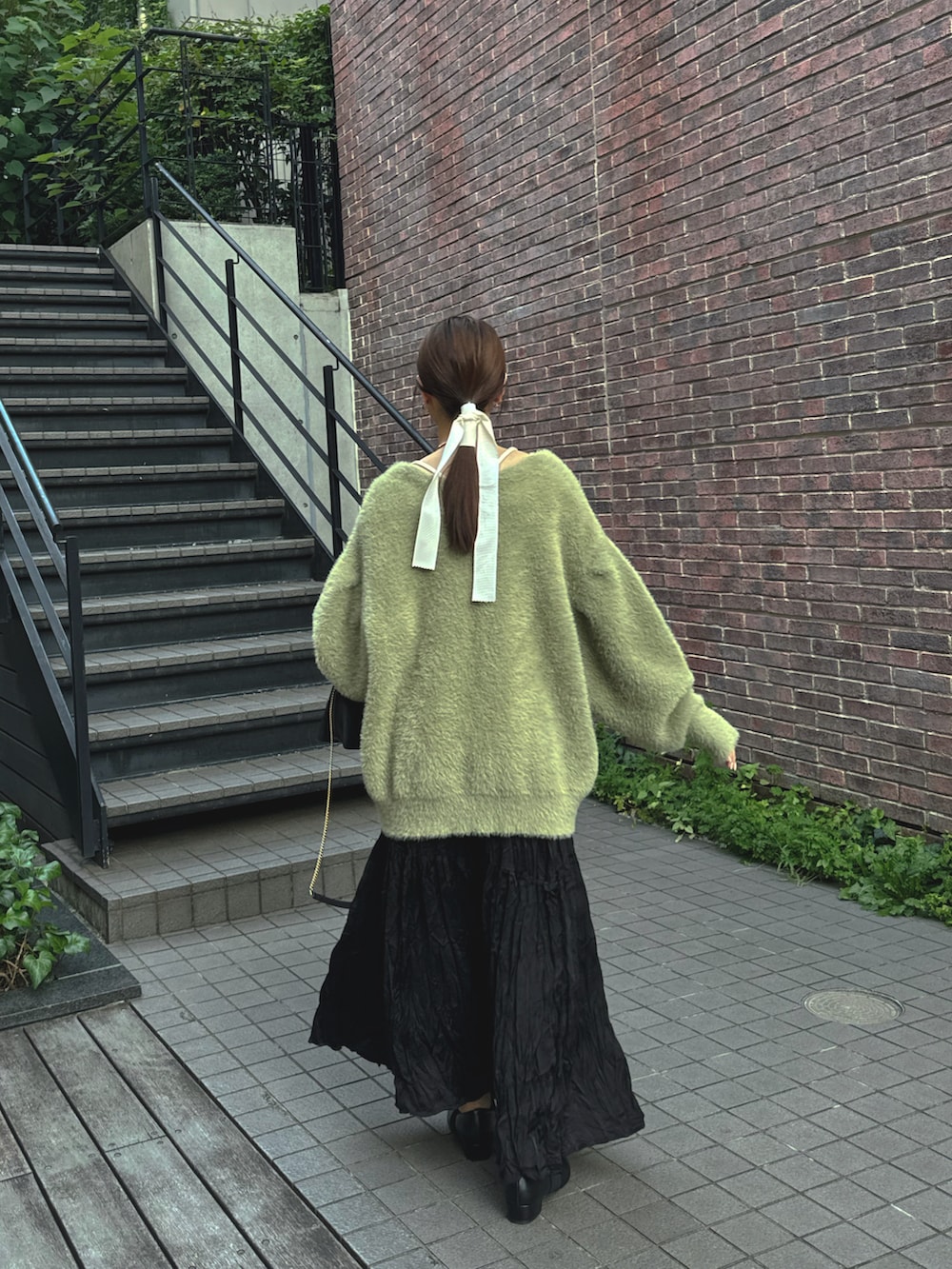 グリーン系のカーディガン/ボレロ、ブラック系のスカートを着用したレディースの秋コーディネートの2枚目の写真