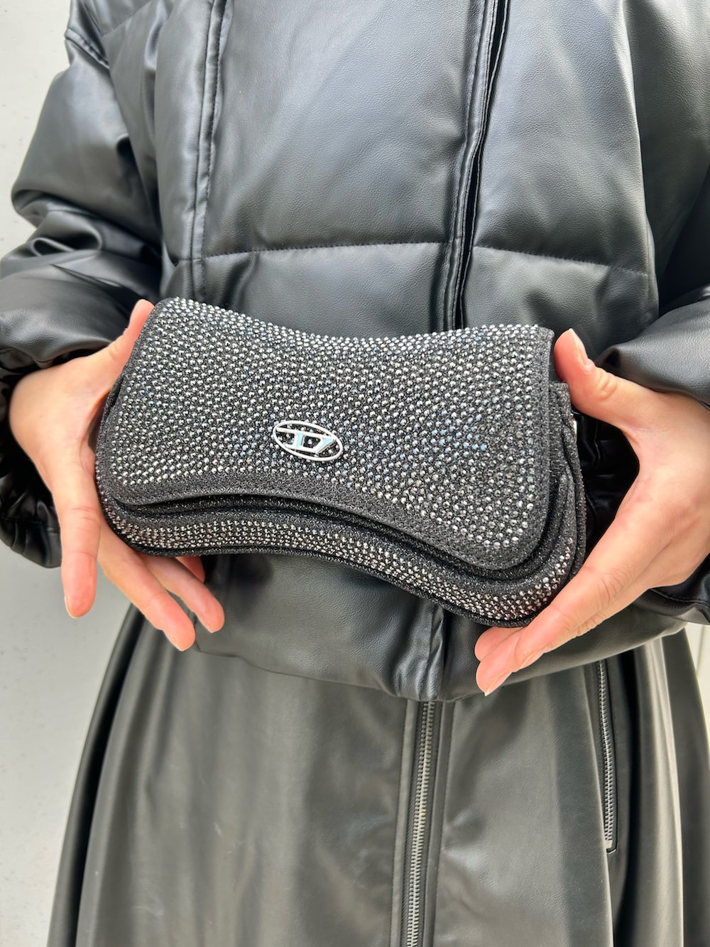 ブラック系のダウンジャケット/コート、ブラック系のショルダーバッグ、ブラック系のワンピースを着用したレディースの冬コーディネートの3枚目の写真