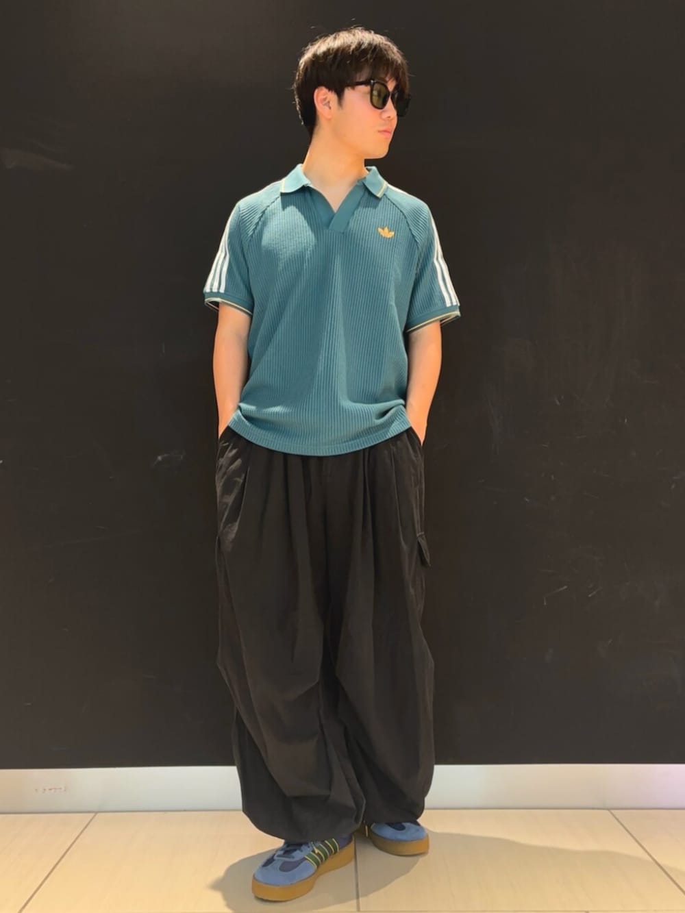 グリーン系のポロシャツ、ブルー系のシューズを着用したメンズの春コーディネートの2枚目の写真