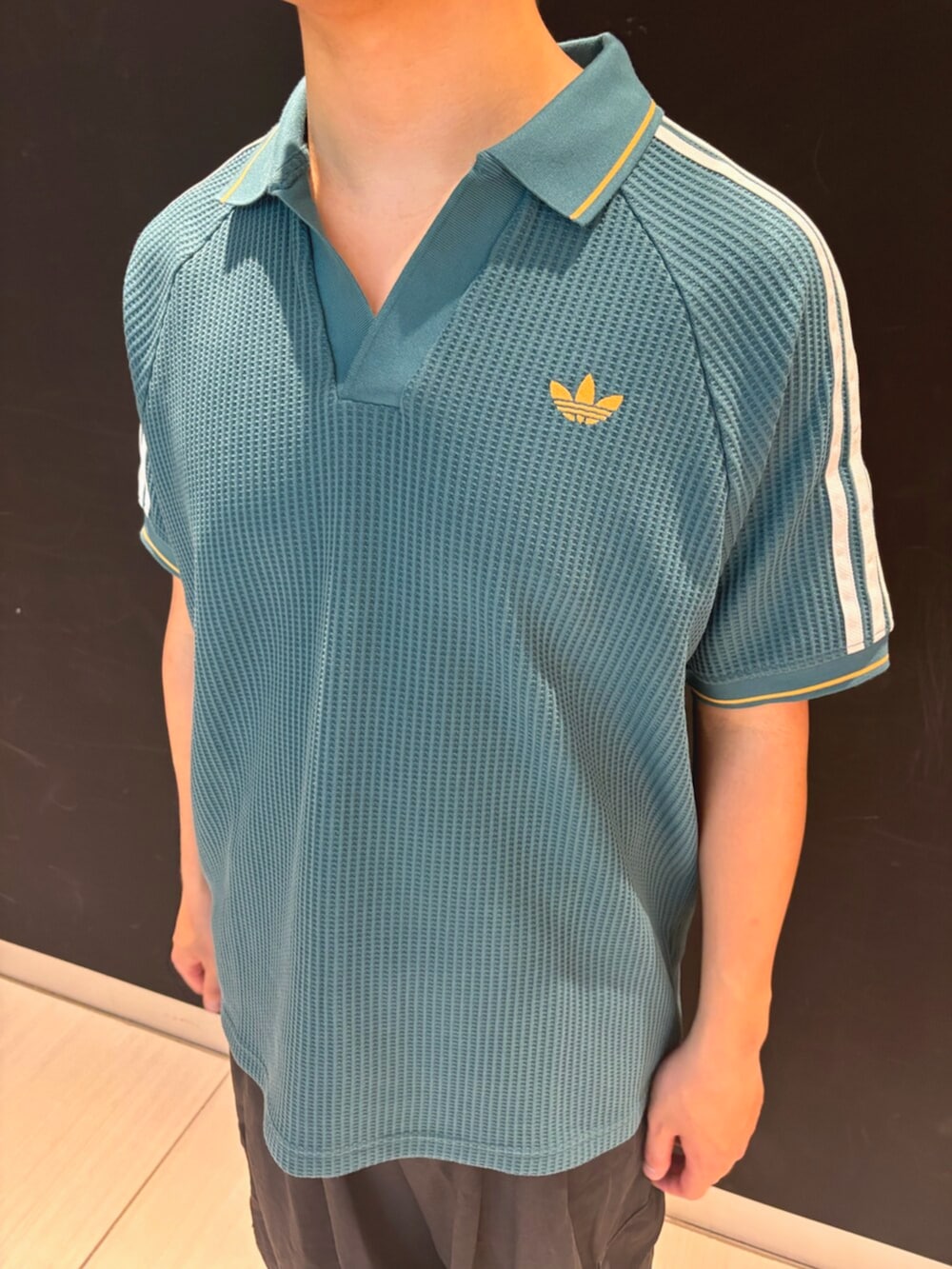 グリーン系のポロシャツ、ブルー系のシューズを着用したメンズの春コーディネートの3枚目の写真