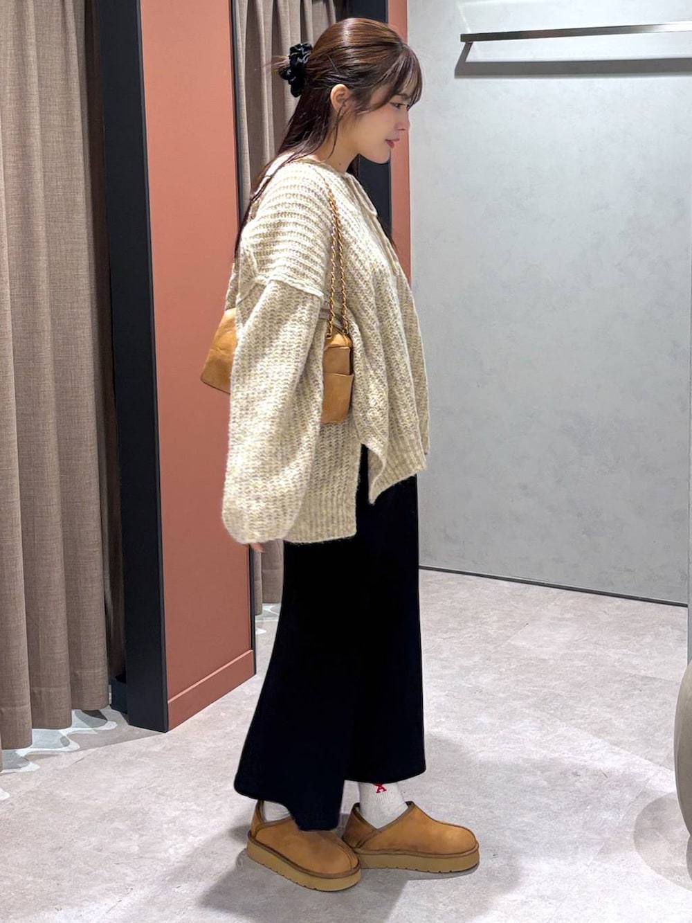 ブラック系のスカート、ホワイト系のニット/セーター、ベージュ系のショルダーバッグを着用したレディースの秋コーディネートの3枚目の写真