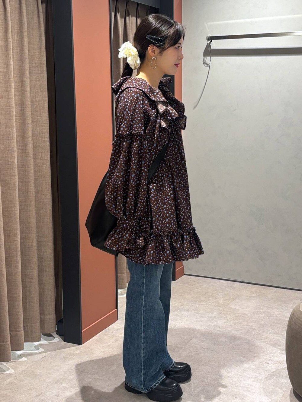 ブラック系のスニーカー、ブルー系のデニムパンツ、ブラック系のショルダーバッグを着用したレディースの秋コーディネートの2枚目の写真